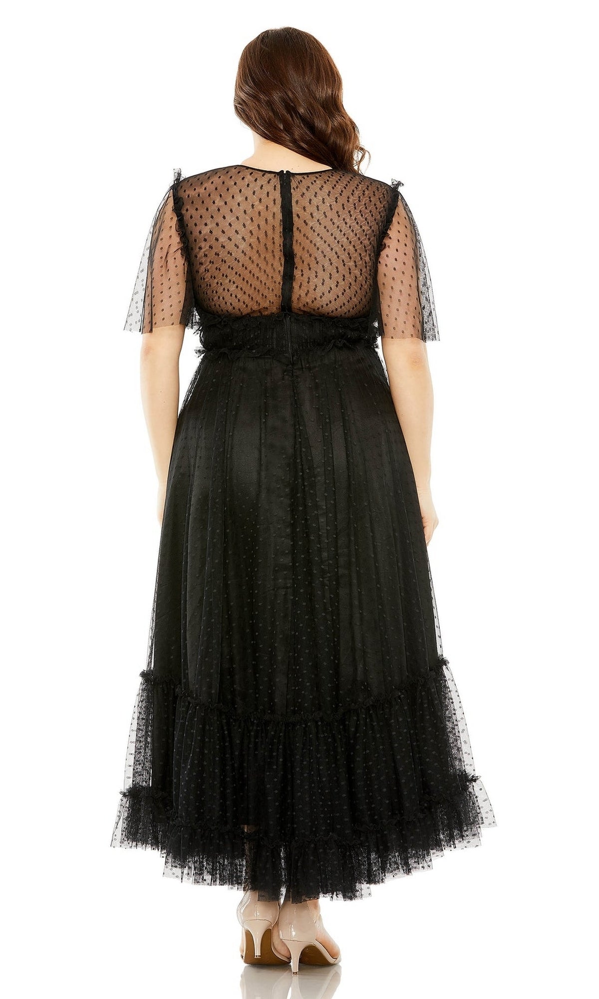 A woman wears the Long Plus-Size Prom Dress 68568 by Mac Duggal, featuring a high neck and sheer polka-dot sleeves and back, standing with her back to the camera against a white background.