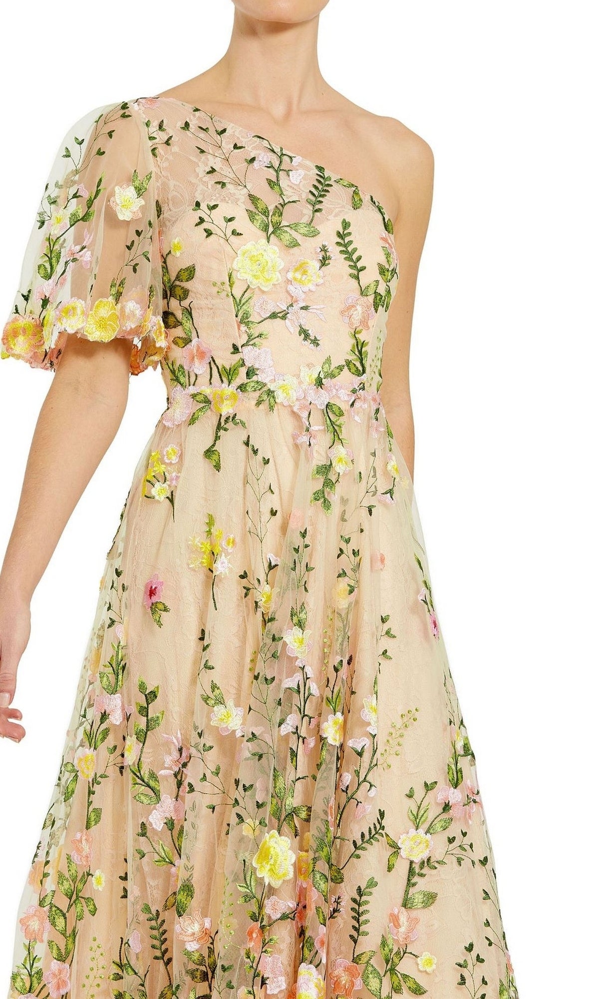 A person wearing the Mac Duggal 68607 One-Shoulder Midi Party Dress, featuring a tea-length cut and sheer floral embroidery in green, pink, and yellow on a beige background.