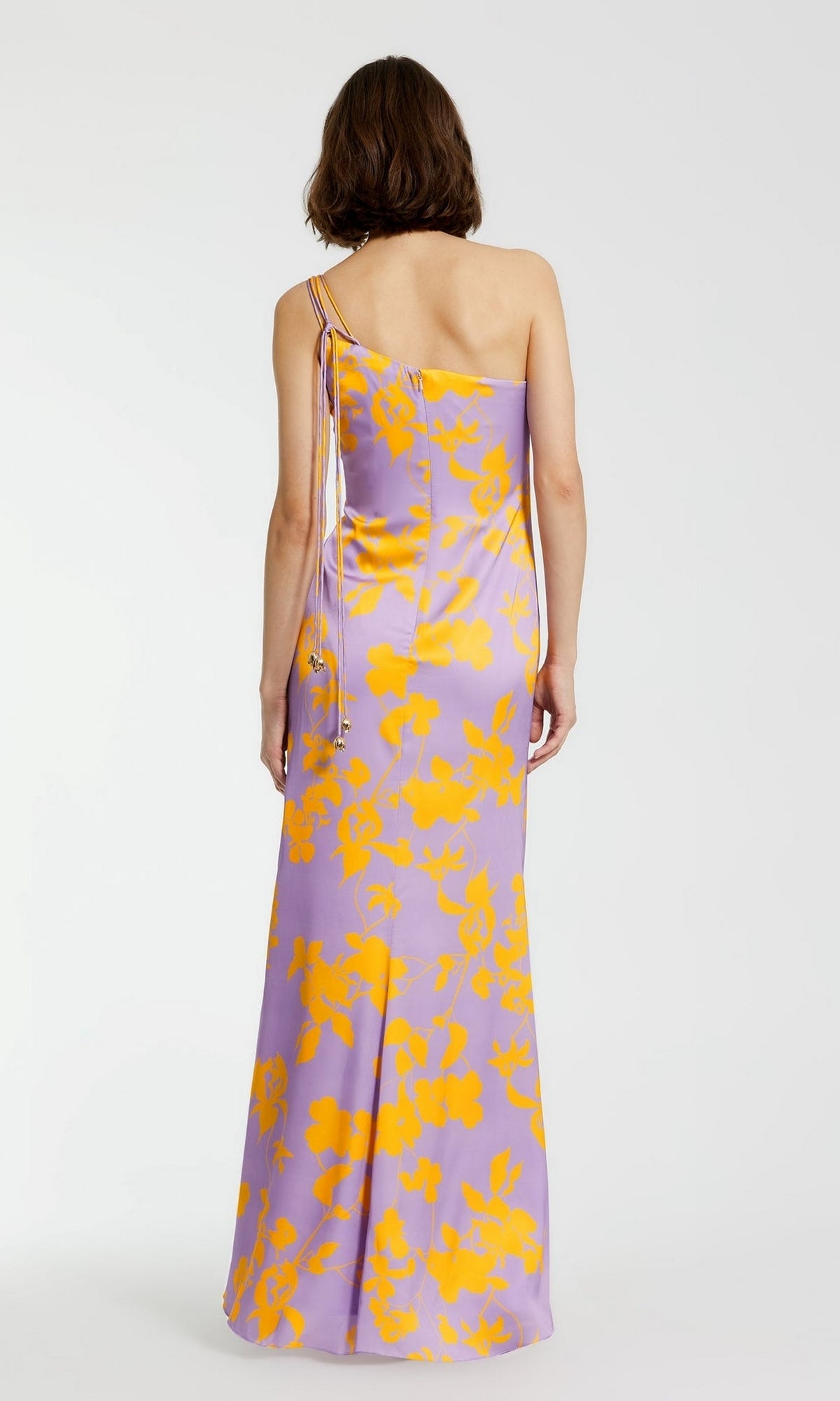 A person is shown from the back in the Long Formal Dress 68771 by Mac Duggal, a floor-length, one-shoulder gown featuring an orchid print with yellow floral patterns against a plain background.