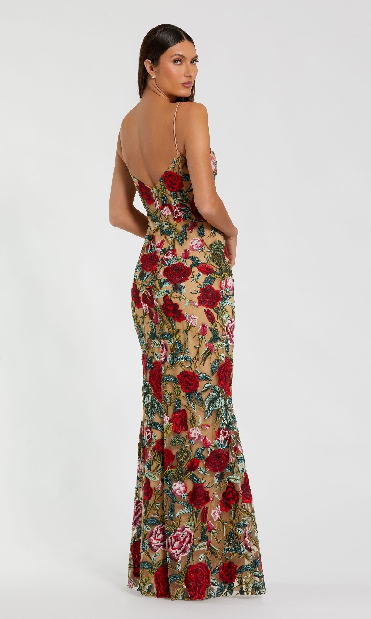 A woman wearing the Mac Duggal 68884 Long Floral-Lace Formal Dress— a floor-length nude gown with floral lace and thin straps—stands against a plain white background, glancing over her shoulder.