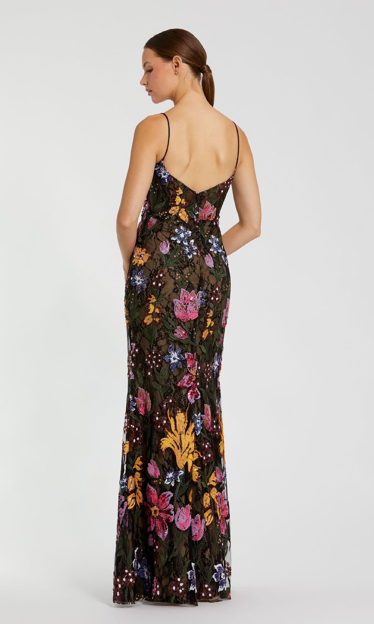 A woman stands with her back to the camera in the Mac Duggal 68885 Embroidered Long Formal Dress—an elegant black, floor-length gown adorned with colorful floral embroidery, ideal for special occasions.