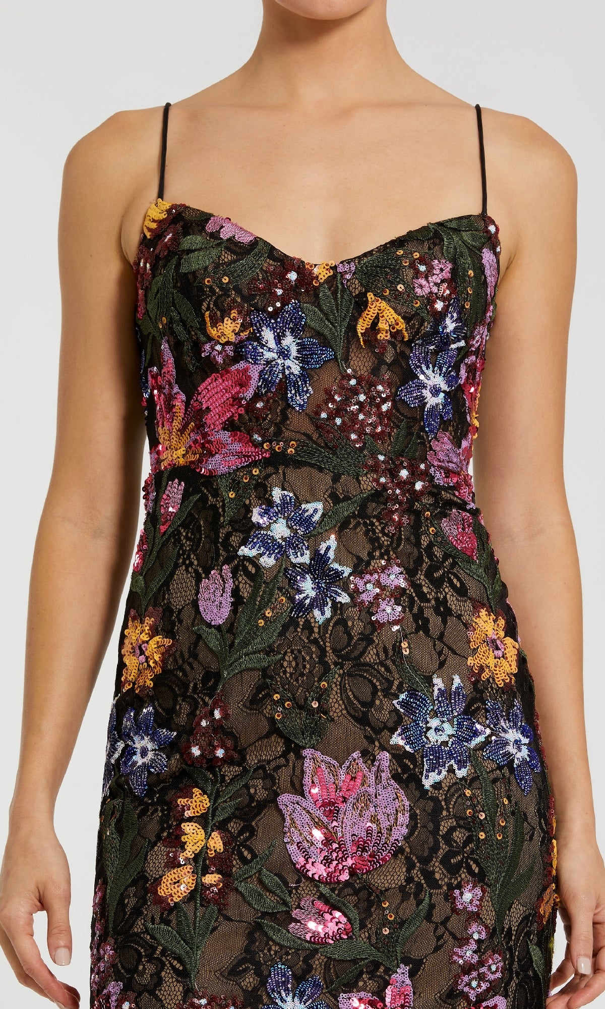 A woman wears the Embroidered Long Formal Dress: Mac Duggal 68885—a long black formal gown with thin straps, floral embroidery, black lace overlay, and colorful sequins—an elegant choice for special occasions.