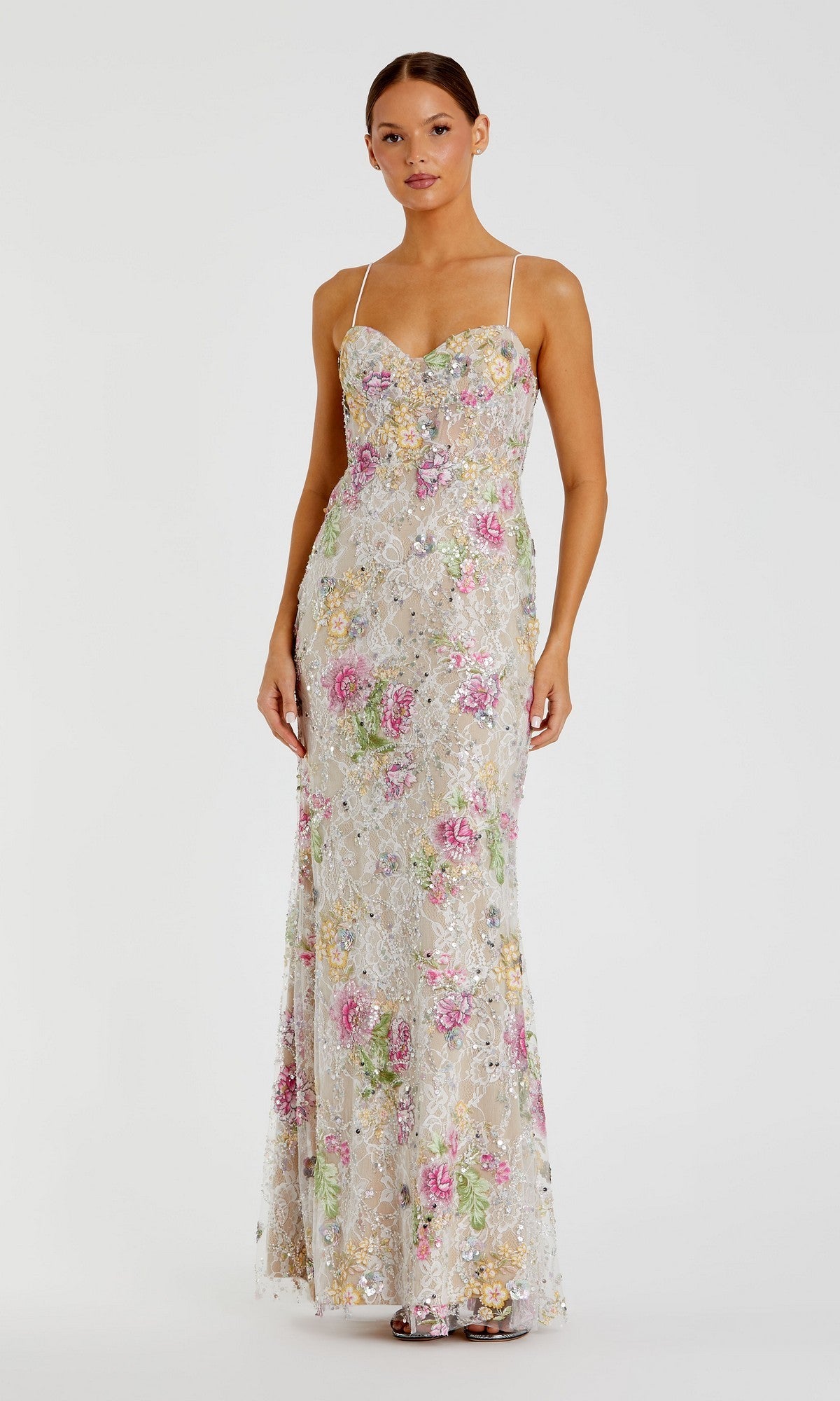 A woman is wearing the Mac Duggal 68891 long formal dress in Ivory Multi, a sleeveless, floor-length gown with thin straps, a fitted silhouette, and pastel floral sequin embroidery.