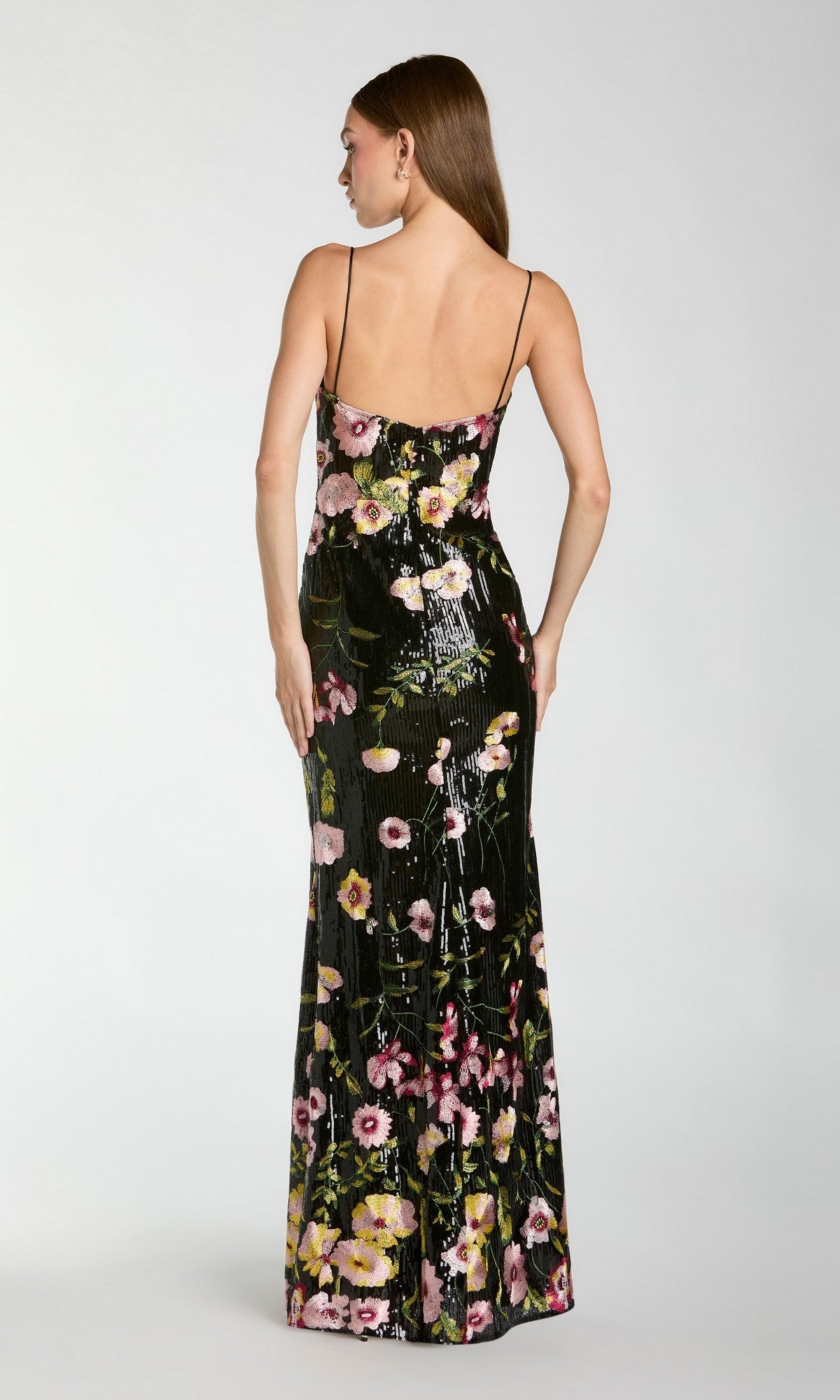 A woman faces away, wearing the Mac Duggal 68896 Long Formal Dress—a sleeveless gown with thin straps and a vibrant floral pattern.