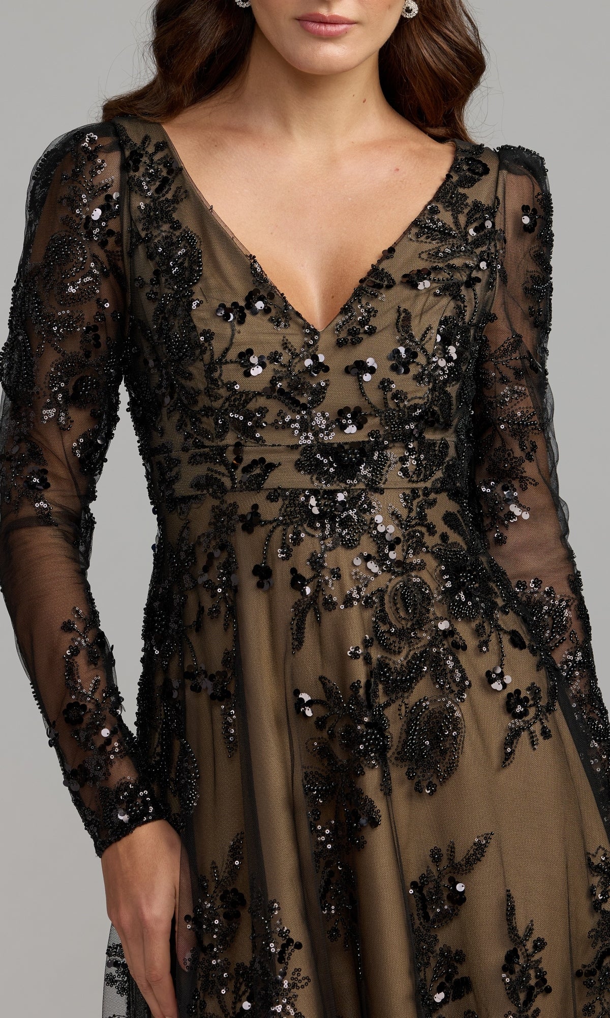 A woman wearing the Mac Duggal 68908 Long Sleeve Long Formal Dress, featuring sheer black fabric with intricate sequin and bead embroidery over a nude underlayer.
