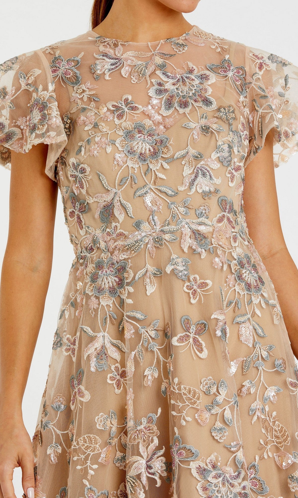 A woman models the Mac Duggal 68920 Tea-Length Party Dress, featuring short sleeves and nude mesh adorned with intricate pastel floral beaded embroidery. The fit-and-flare silhouette accentuates her upper body, while her head and lower body are out of frame.