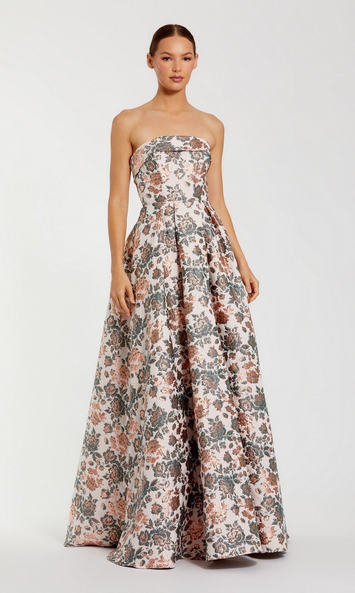 A woman stands against a plain white background wearing the Mac Duggal 68945 long formal dress, a strapless ball gown in a gold multi brocade floral pattern.