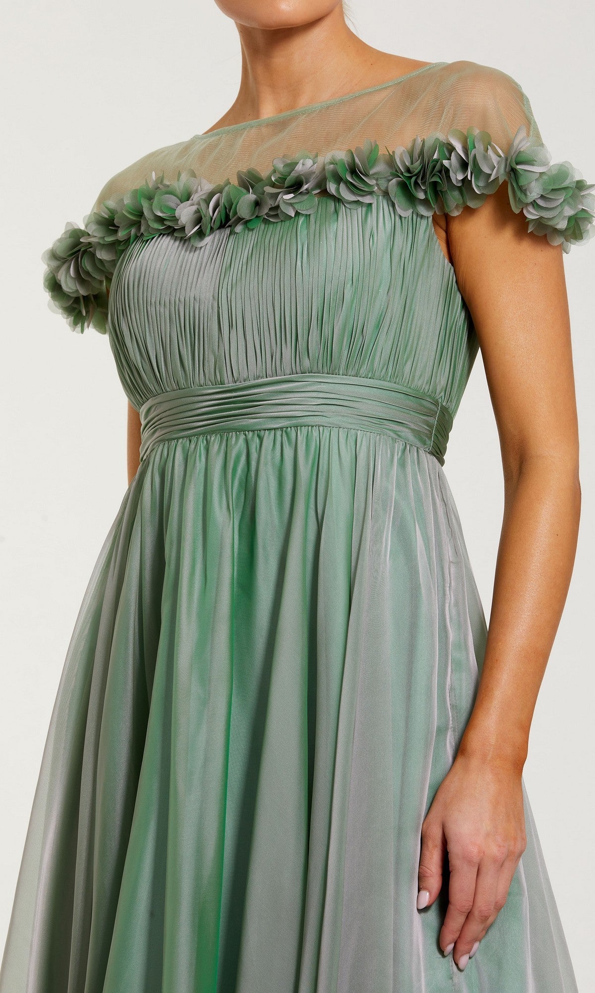 A woman wearing the Mac Duggal 68966 tea-length party dress in light green, featuring an off-shoulder fit-and-flare silhouette with a ruched bodice, sheer neckline, and floral detailing along the top edge.