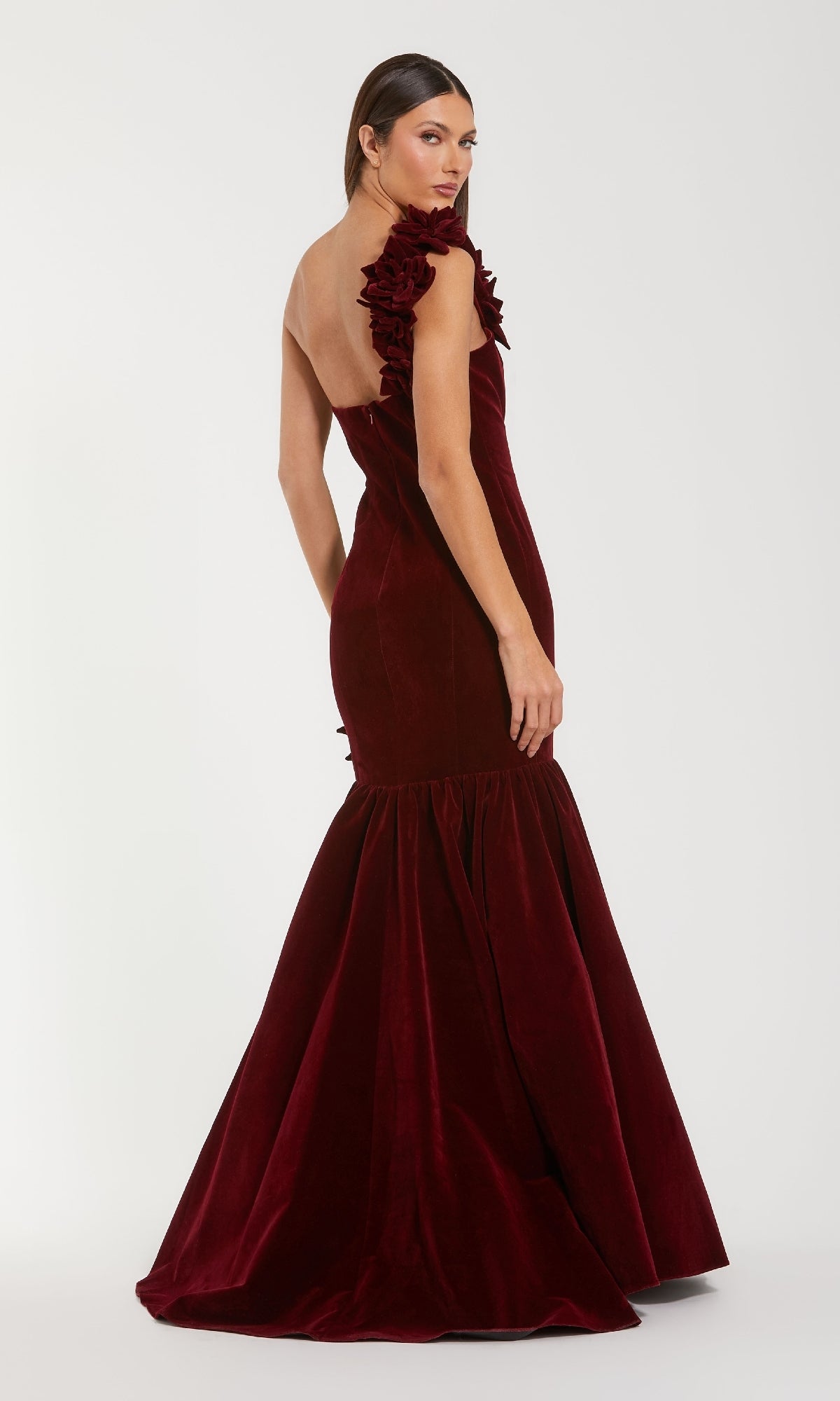 A woman models the Mac Duggal 68983 One-Shoulder Velvet Formal Dress in deep red, featuring a ruffled shoulder and mermaid silhouette, against a plain white background—a striking evening gown ensemble.
