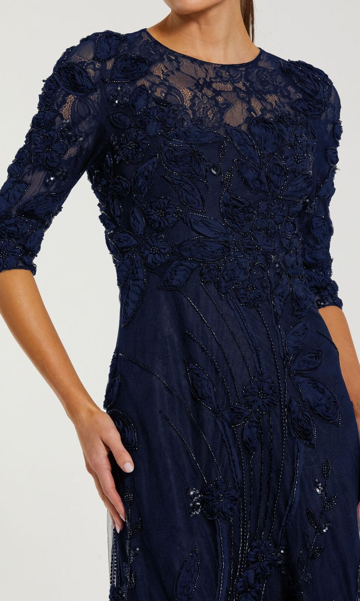 A woman wearing the Mac Duggal 69016 Long Sleeve Beaded Formal Gown, a navy blue dress with floral embroidery and bead detailing—ideal for the mother of the bride.