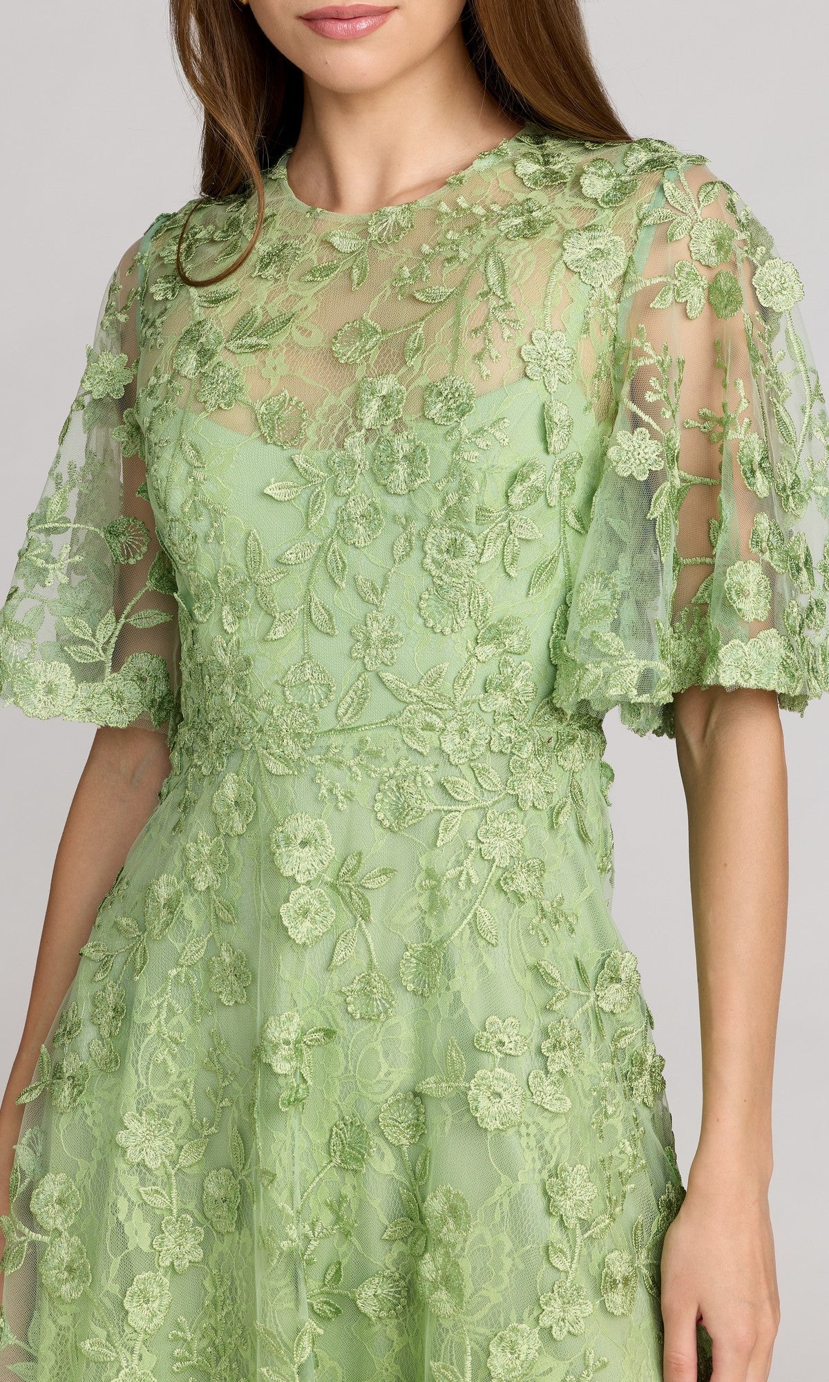 Woman wearing the Mac Duggal 69036 Lace Midi Wedding Guest Dress in light green, featuring short sleeves, floral embroidery, and sheer detailing—shown head to mid-thigh—a stunning choice for wedding guests.