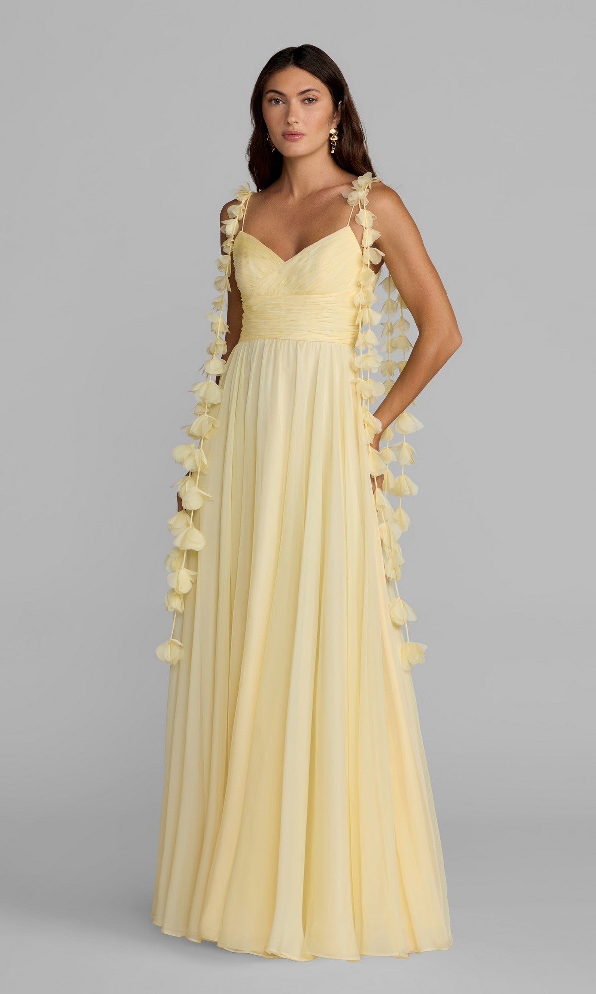 A woman wearing the Mac Duggal 69086 long formal dress in butter—a floor-length chiffon gown with a sweetheart neckline and floral ribbon details on the straps—stands against a plain gray background.