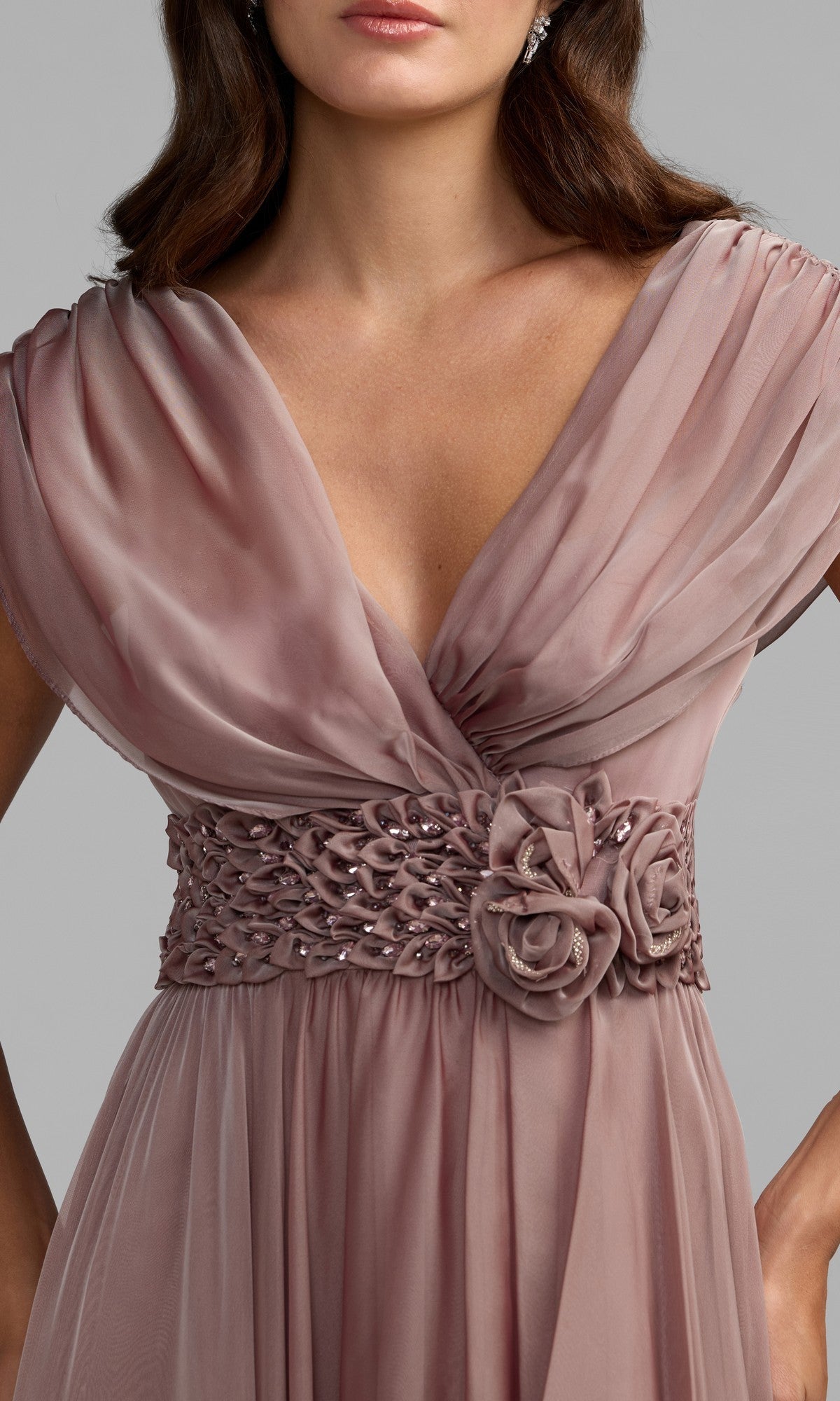 A woman wearing the Long Formal Dress: Mac Duggal 69089, featuring a mauve chiffon fabric with a v-neckline, draped sleeves, crystal-embellished waistband, and delicate rosette details at the waist—a timeless silhouette exuding classic elegance.