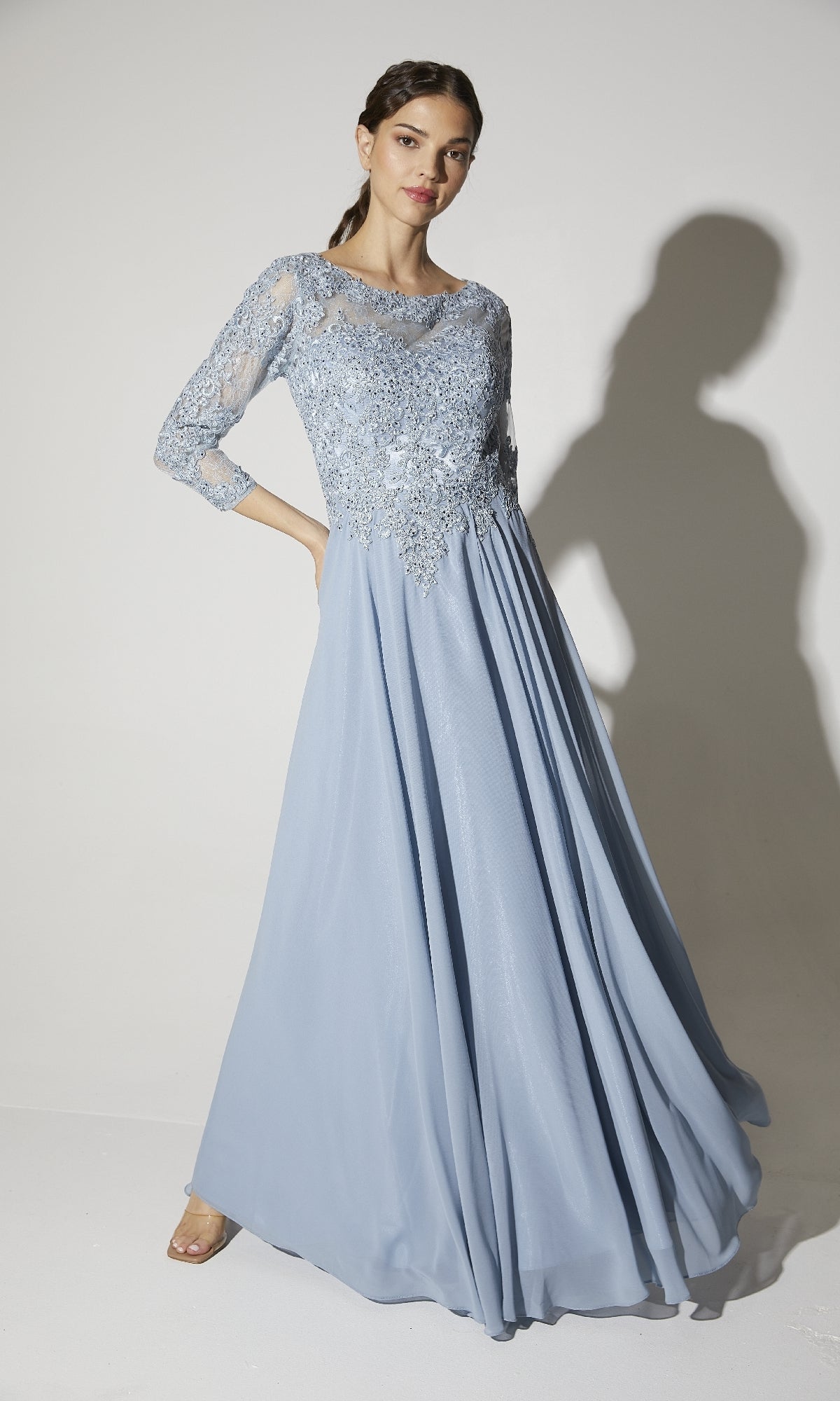 A woman poses gracefully against a white background in the Eureka 6909 long-sleeve formal dress, featuring a light blue lace bodice and delicate sleeves.
