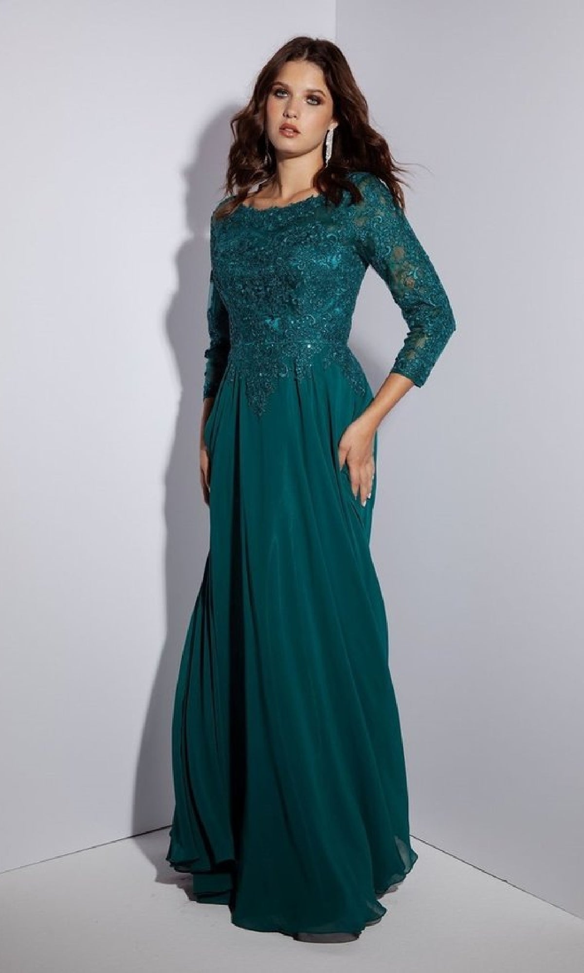 A woman models the Eureka 6909 long formal dress in teal, featuring an A-line silhouette, intricate lace bodice, and elegant long lace sleeves, set against a plain background.
