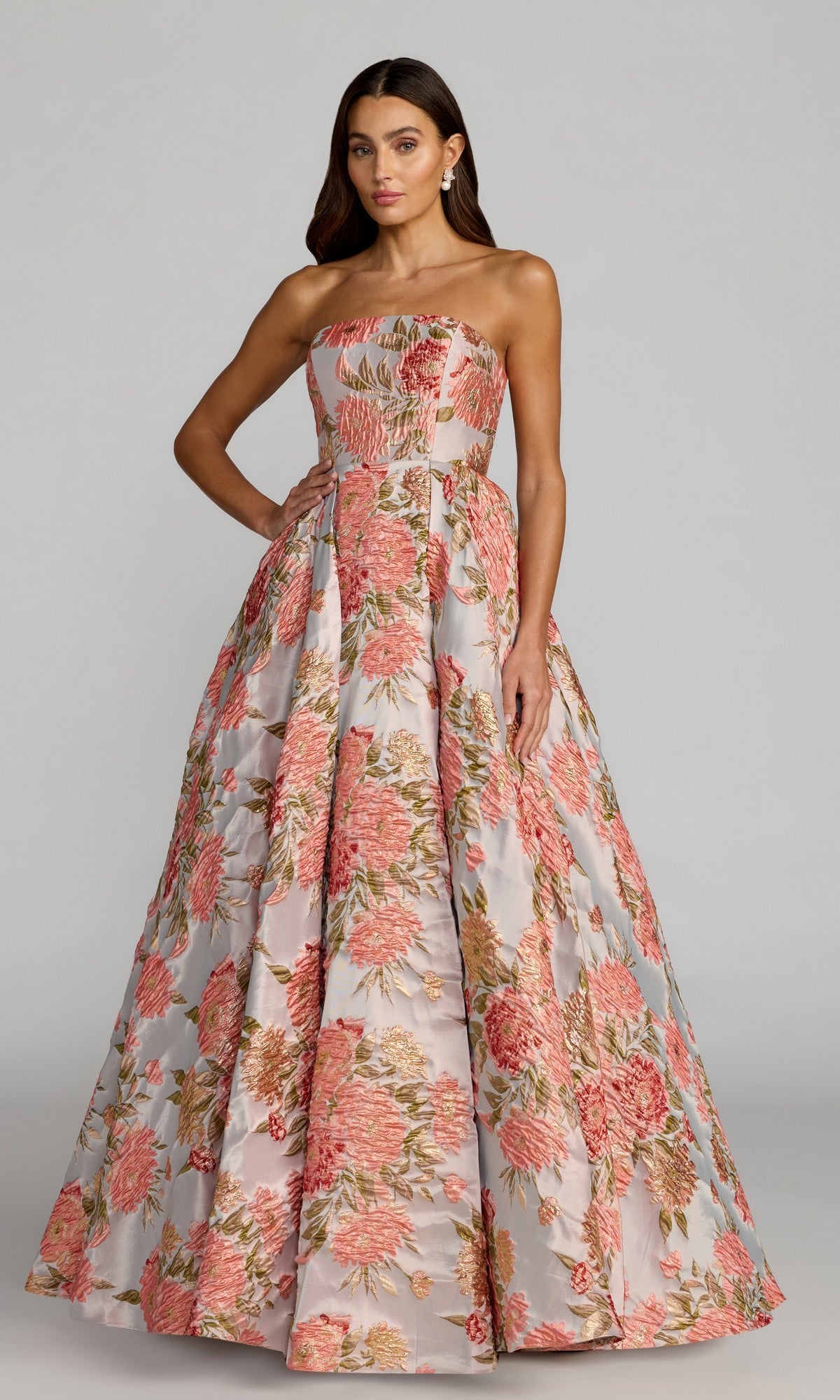 A woman wearing the Mac Duggal 69169 long formal dress in Pastel Multi, a strapless, floor-length A-line gown featuring a pink, green, and gold floral brocade pattern, stands against a plain background.