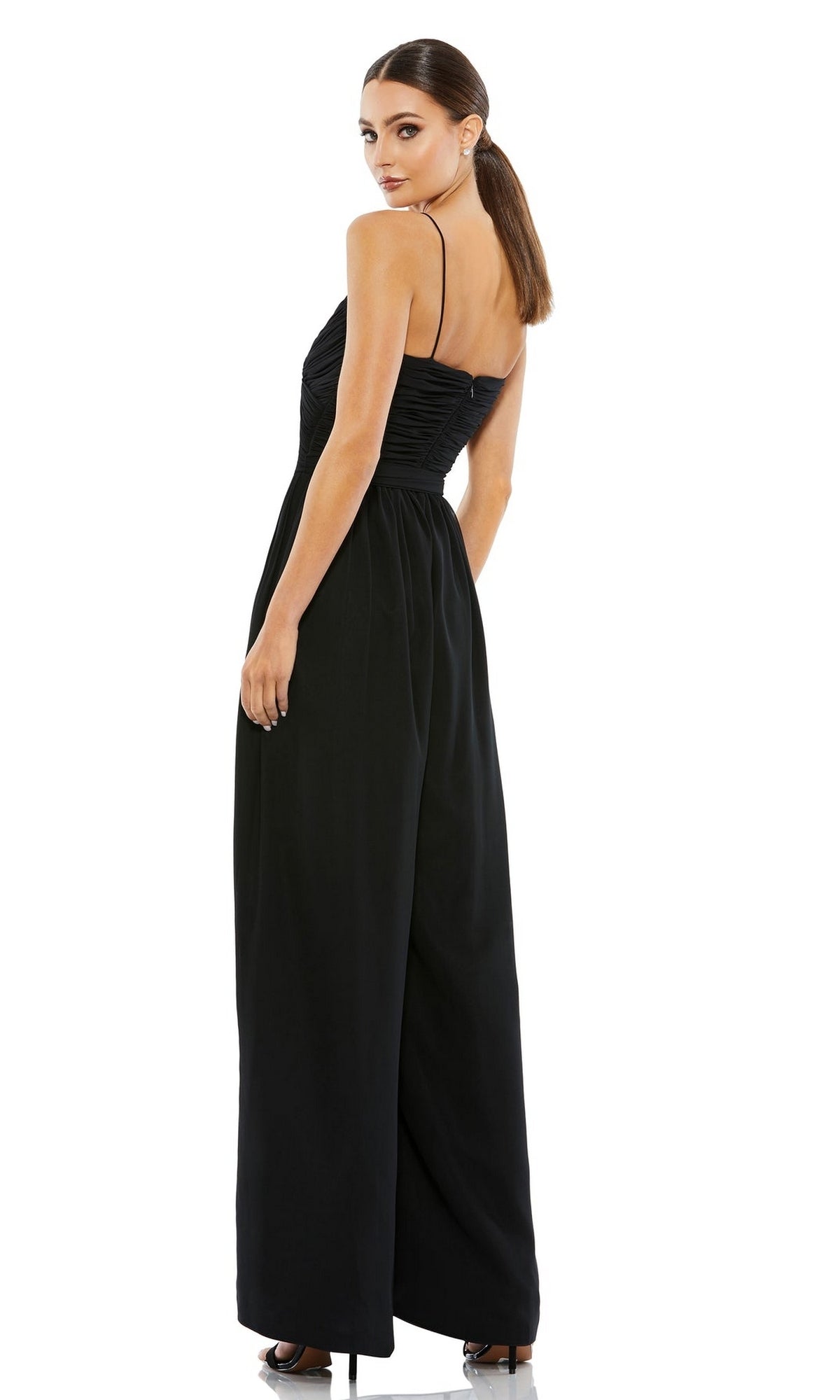 A woman models the Mac Duggal 70100 Flowing Wide-Leg Formal Jumpsuit with spaghetti straps, posing against a white background and glancing over her shoulder.