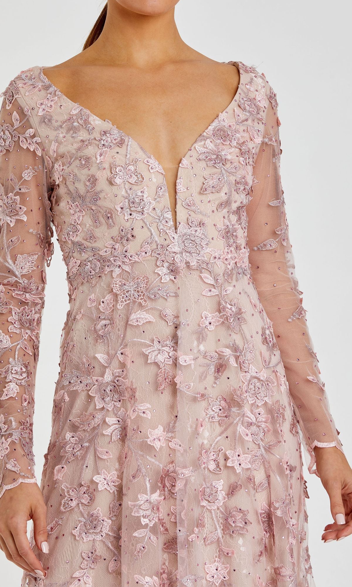 A woman wearing the Mac Duggal 70224 long sleeve formal dress in light pink, featuring floral lace embroidery and a deep V-neckline.