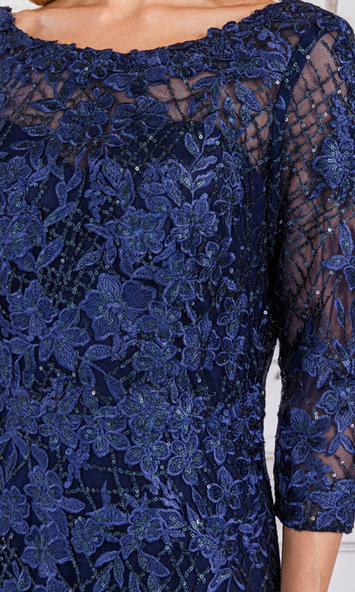 Close-up of a person wearing the Floral-Embroidered Long Sleeve Formal Dress 7045 in navy blue, featuring floral embroidery and sheer three-quarter sleeves.