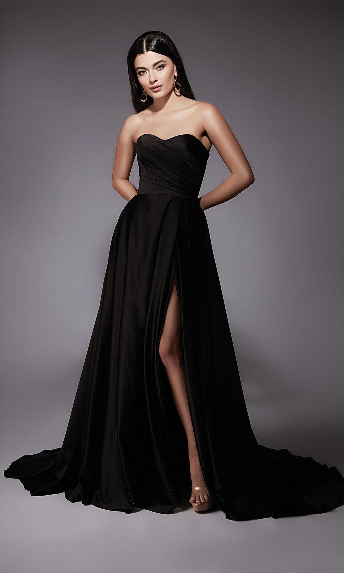 A woman models the Alyce 7088 Long Formal Dress in black, featuring a strapless design and high slit, set against a plain gray background.