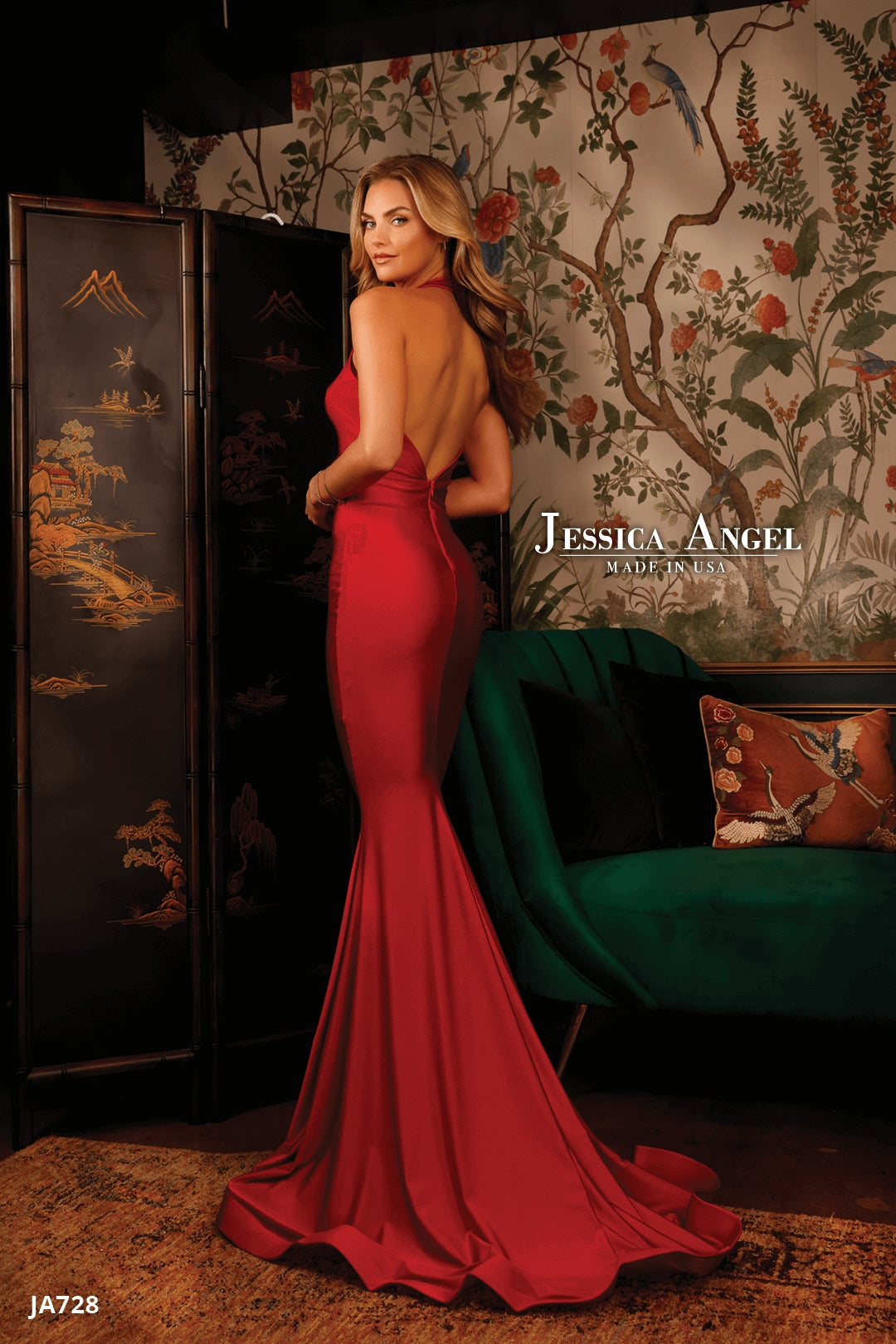 A woman in a fitted, backless red mermaid gown stands in an ornate room with floral wallpaper and a green sofa. Text: