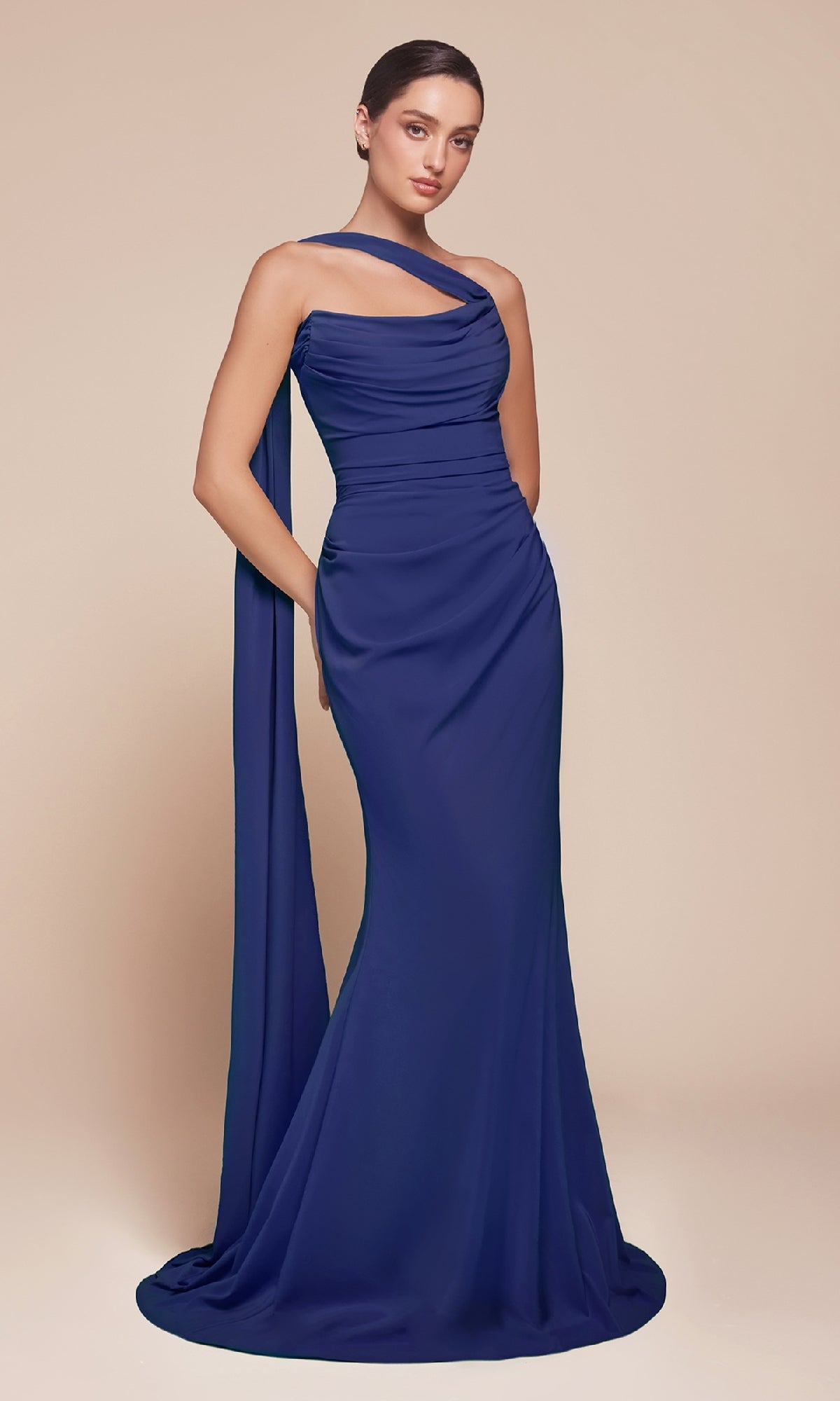 A person stands against a plain beige background wearing the Ladivine 7433 Multi-Way Long Chiffon Prom Dress in royal blue, featuring floor-length chiffon fabric and a draped sash.