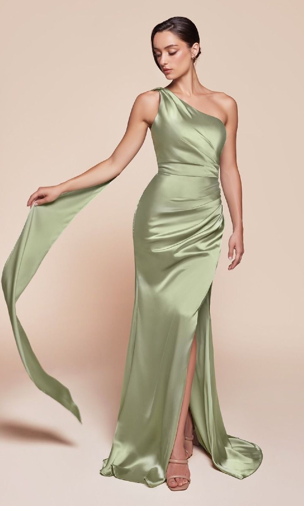 A woman poses in the One-Shoulder Sash Long Prom Dress: Ladivine 7454—a light green satin formal dress with a thigh-high slit and draped sash—against a plain beige background.
