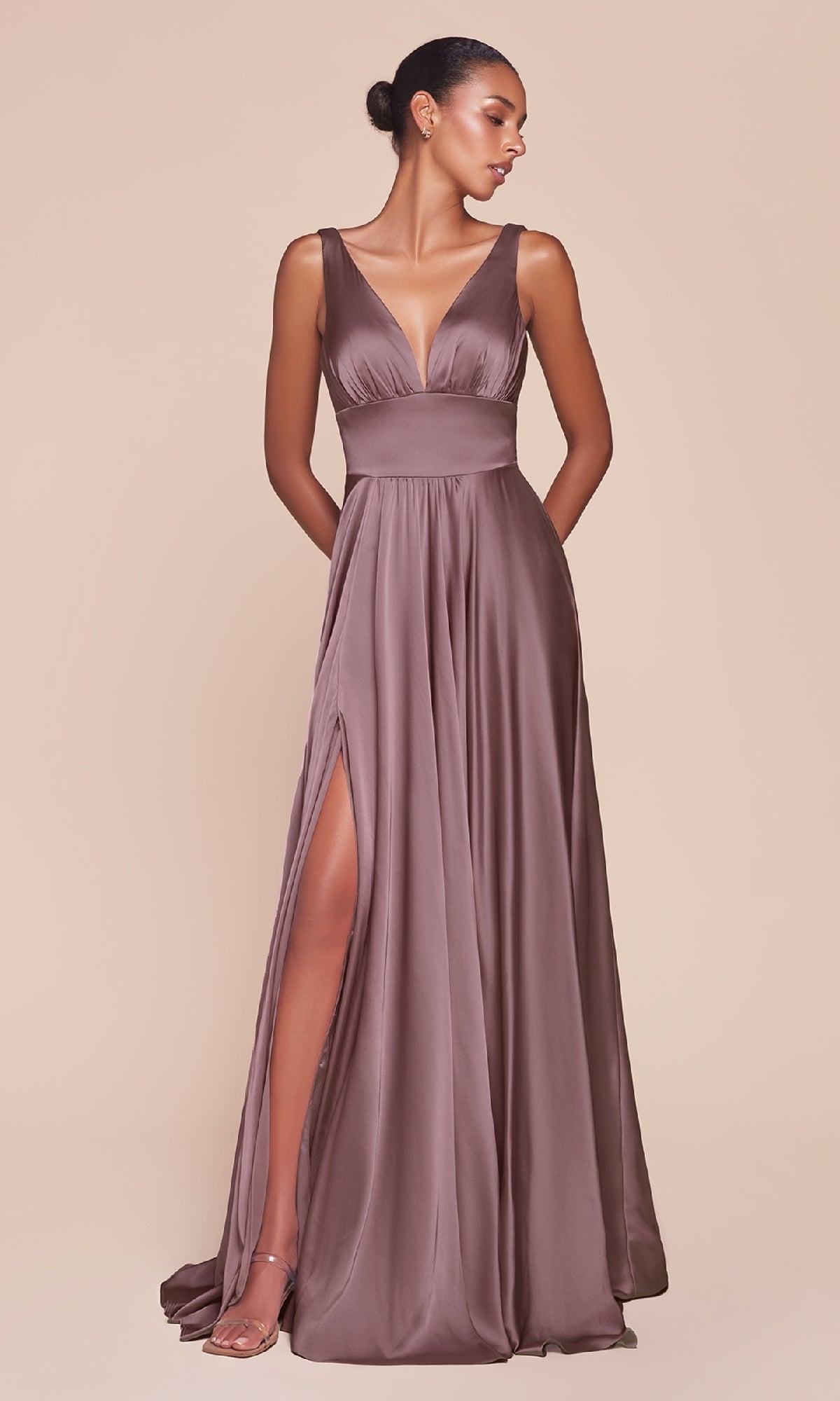 A woman in the Ladivine 7469 Sleeveless Classic Long Prom Dress with a deep V-neckline and thigh-high slit poses against a plain beige background.