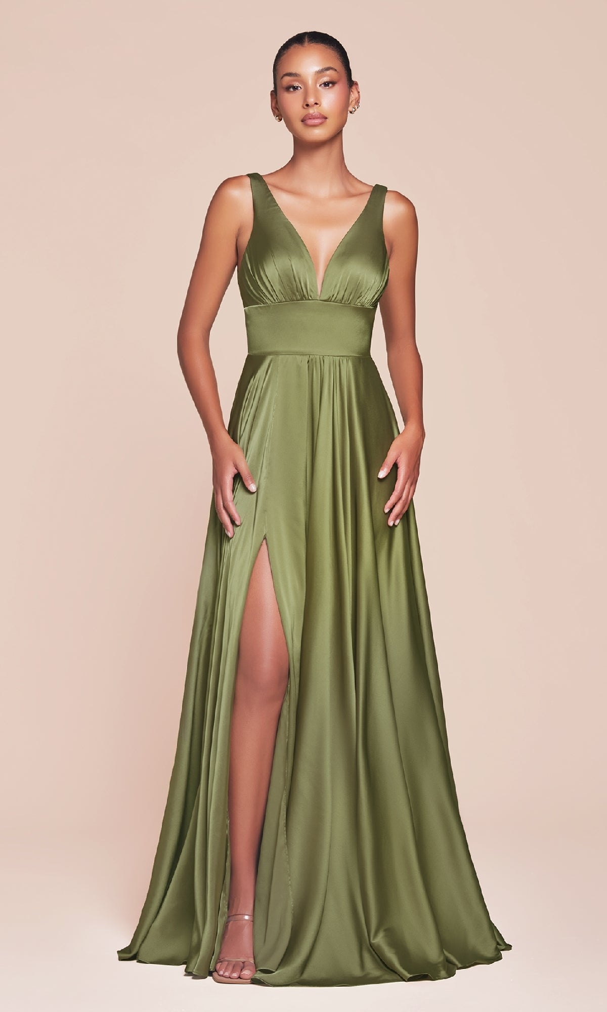 A woman wears the Ladivine 7469 Sleeveless Classic Long Prom Dress in olive green satin, featuring a deep V-neckline, fitted waist, and high side slit, standing against a plain beige background.