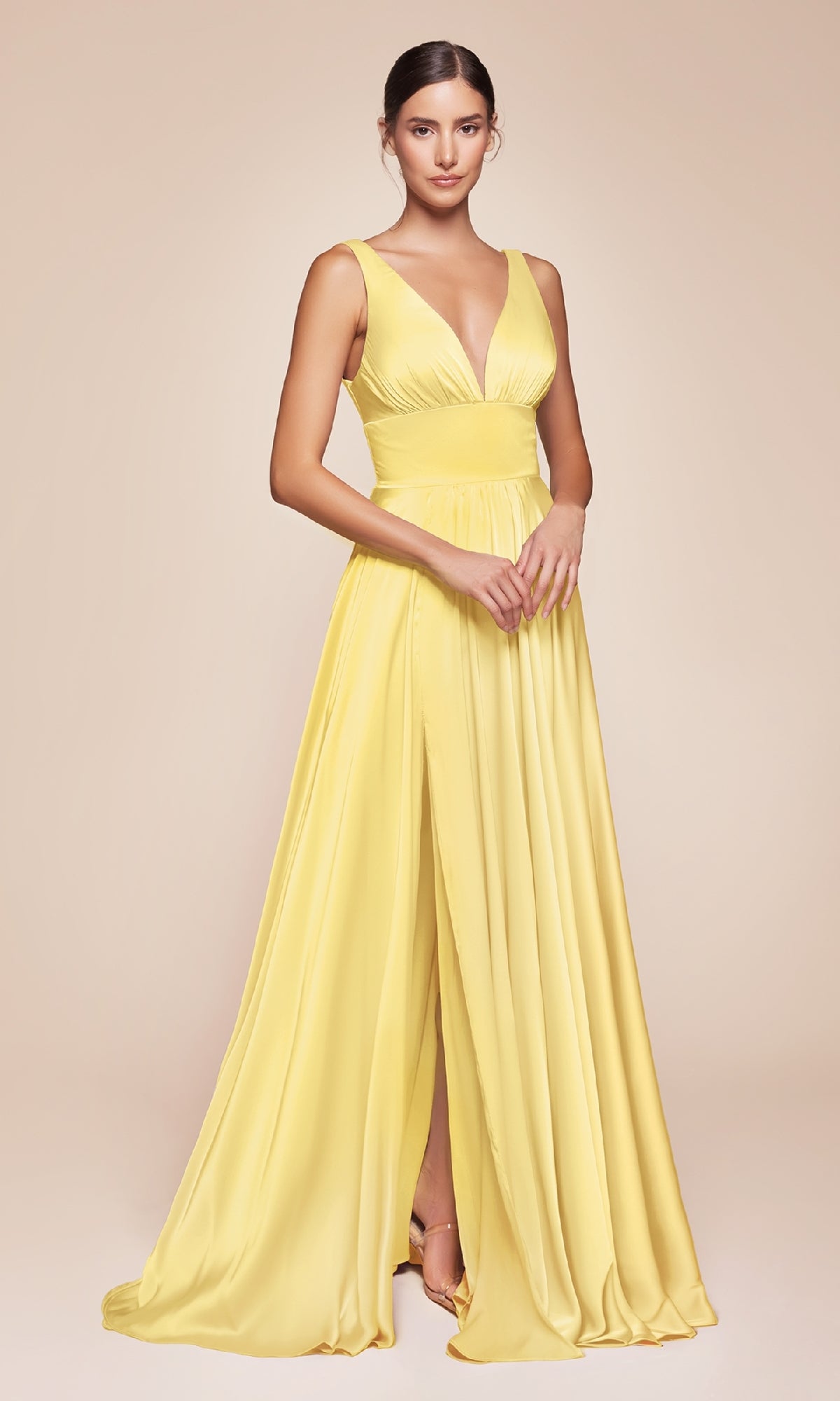 A woman wears the Ladivine 7469 Sleeveless Classic Long Prom Dress in yellow, featuring a v-neck and high slit, set against a plain beige background.