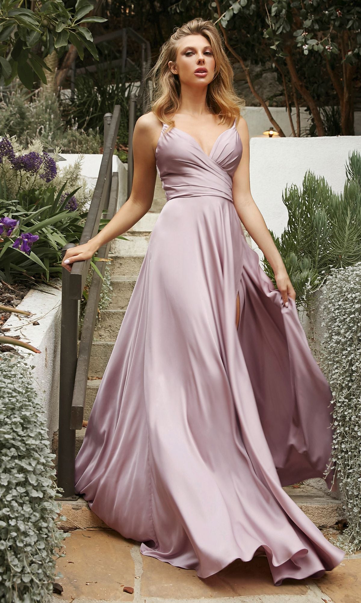 A woman wearing the Classic Long Satin Formal Prom Dress (Ladivine 7485) in light purple stands on outdoor stone steps surrounded by greenery.