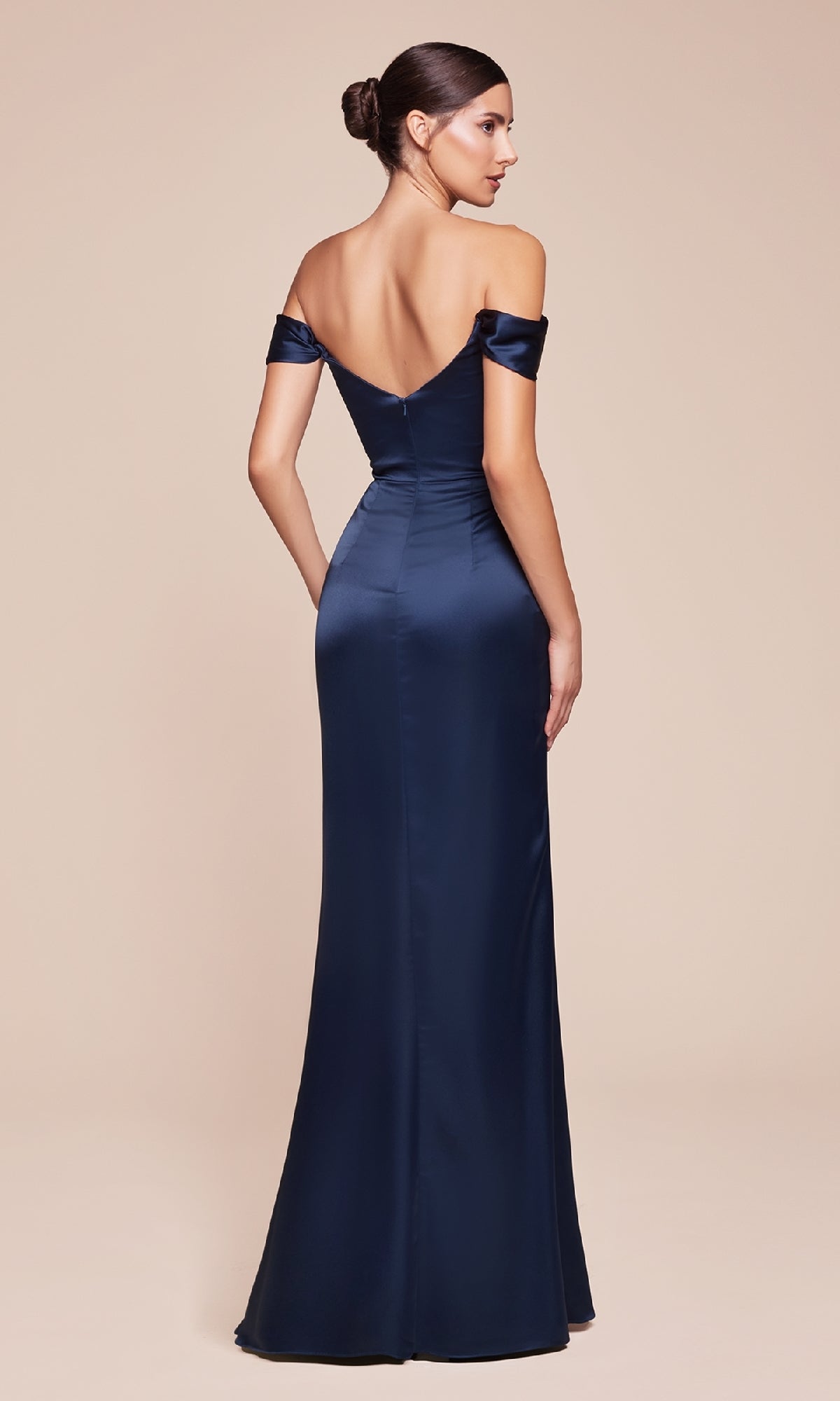 Woman wearing the Cowl-Neck Long Satin Prom Dress (Ladivine 7492-1) in navy blue, featuring a fitted, off-the-shoulder design and floor-length hem, photographed from the back against a plain beige background.