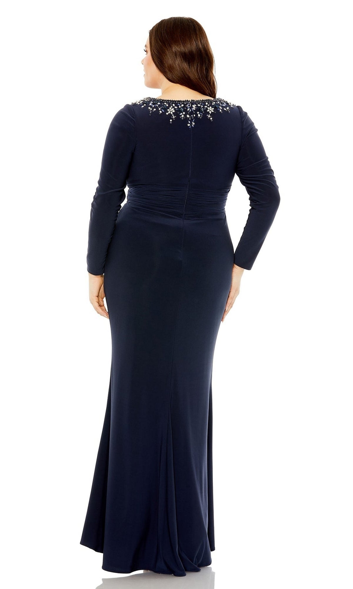 A woman wearing the Long Plus-Size Prom Dress 77023 by Mac Duggal, featuring long sleeves, a navy blue hue, and an embellished neckline, stands with her back to the camera.