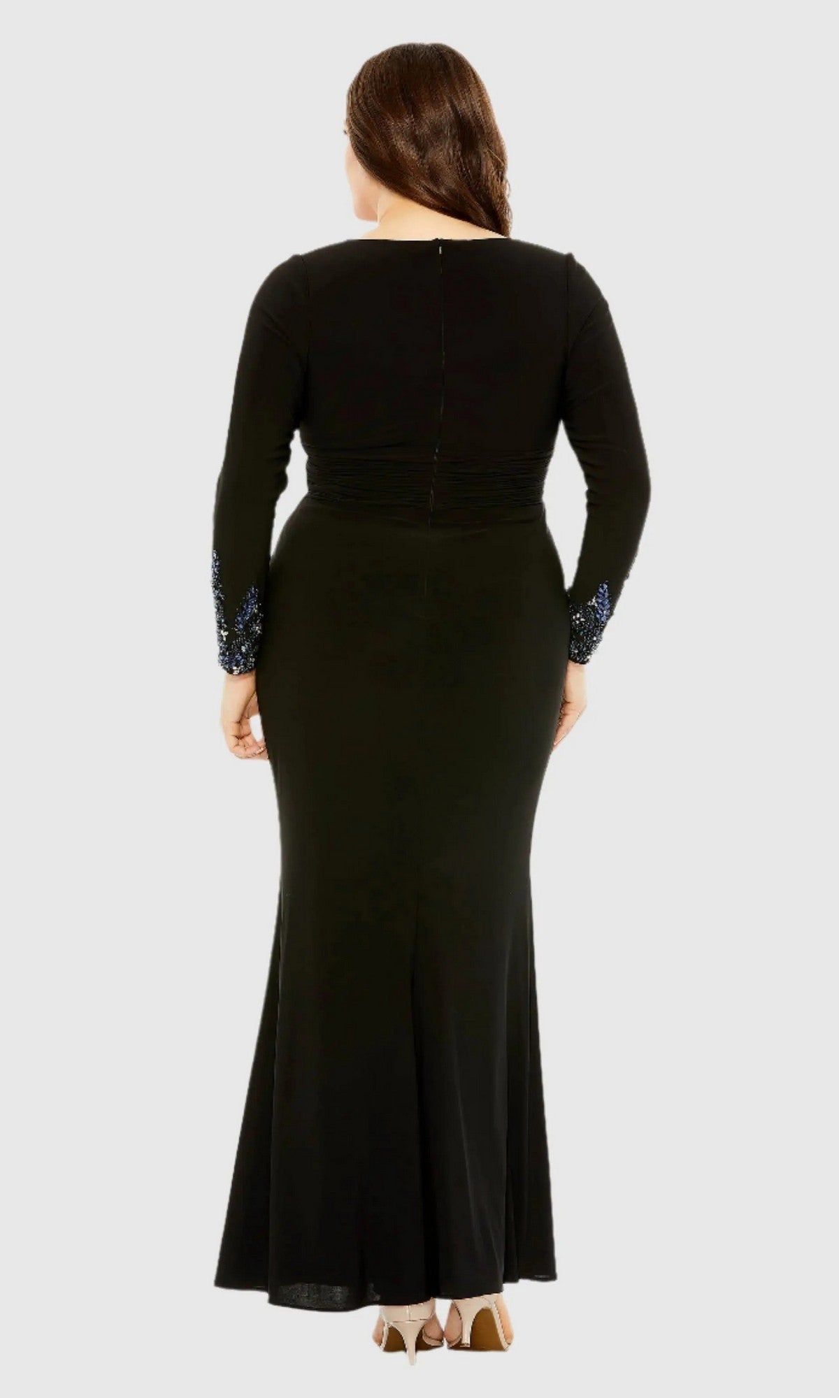 A person stands with their back to the camera, wearing the Mac Duggal 77024 Long Plus-Size Formal Dress in black, featuring long sleeves and decorative cuff details, set against a plain light background.
