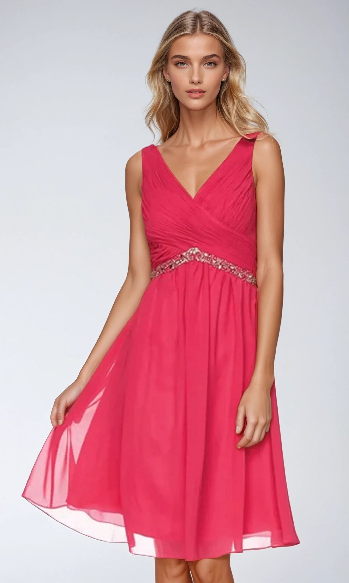 A woman models the Juliet 786 short semi-formal dress—sleeveless, knee-length, pink A-line with a V-neckline and beaded empire waist—standing against a plain light background.