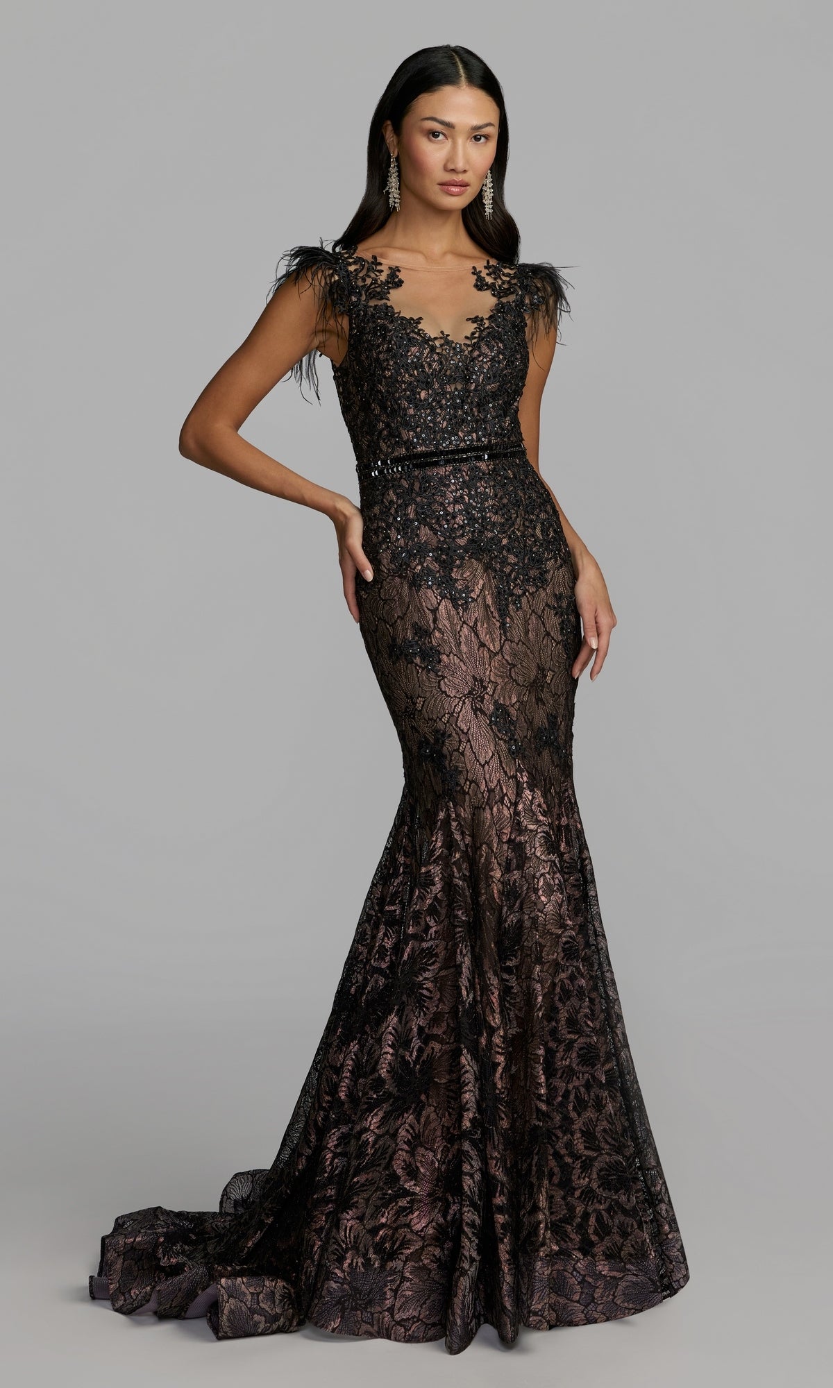 A woman models the Mac Duggal 79230 Feathered Long Lace Formal Dress in black, a sleeveless, floor-length fitted mermaid gown featuring floral lace patterns and feathered shoulder accents, standing against a plain gray background.