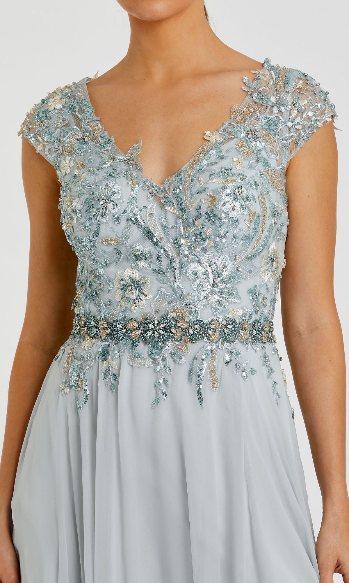 A woman wearing the Mac Duggal 79365 Cap-Sleeve Long Formal Dress in light blue, featuring floral embroidery, bead accents, a deep V neckline, cap sleeves, and a fitted embellished bodice for an elegant look.