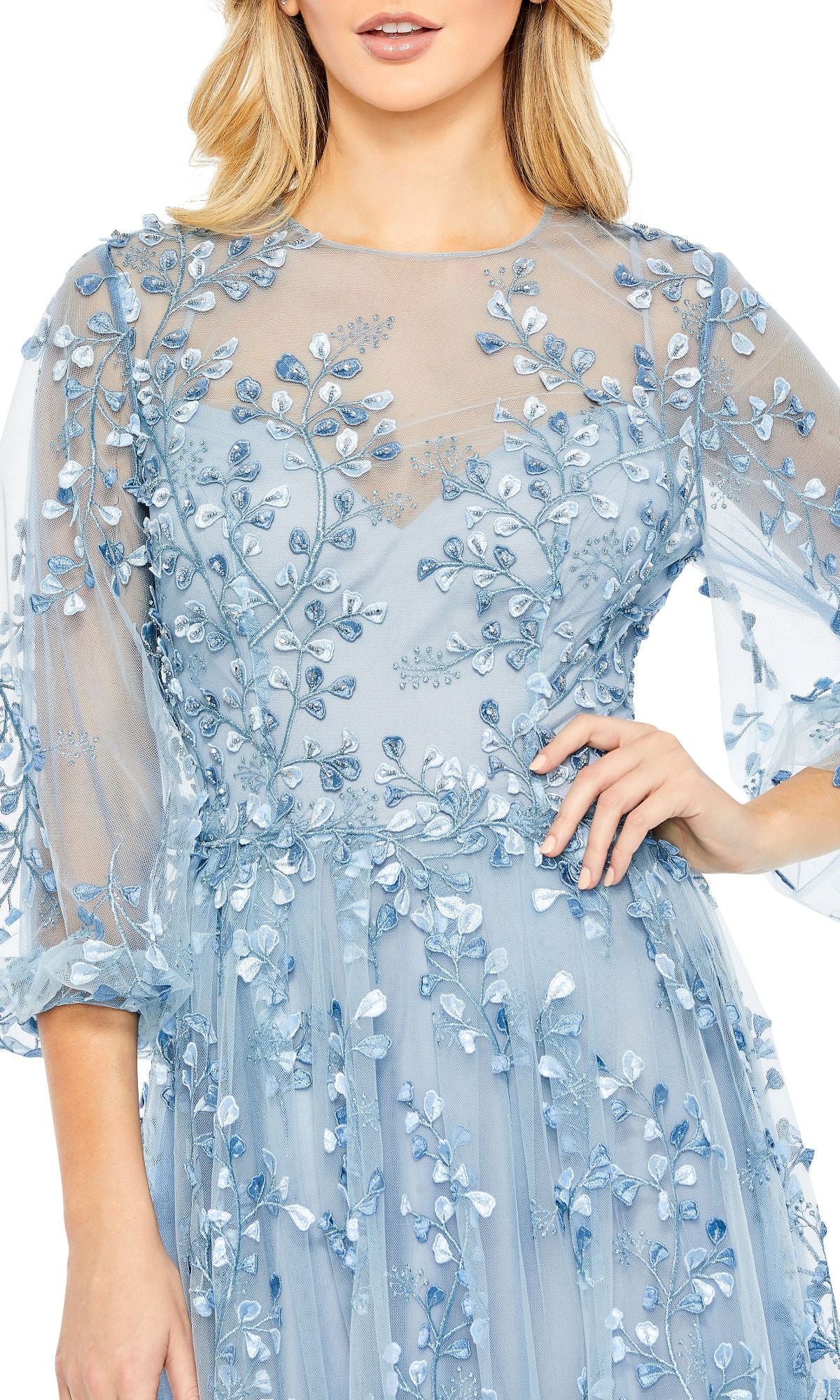 A woman poses with one hand on her hip, wearing the Mac Duggal 79399 long sleeve blue formal dress; her face is partially out of frame.