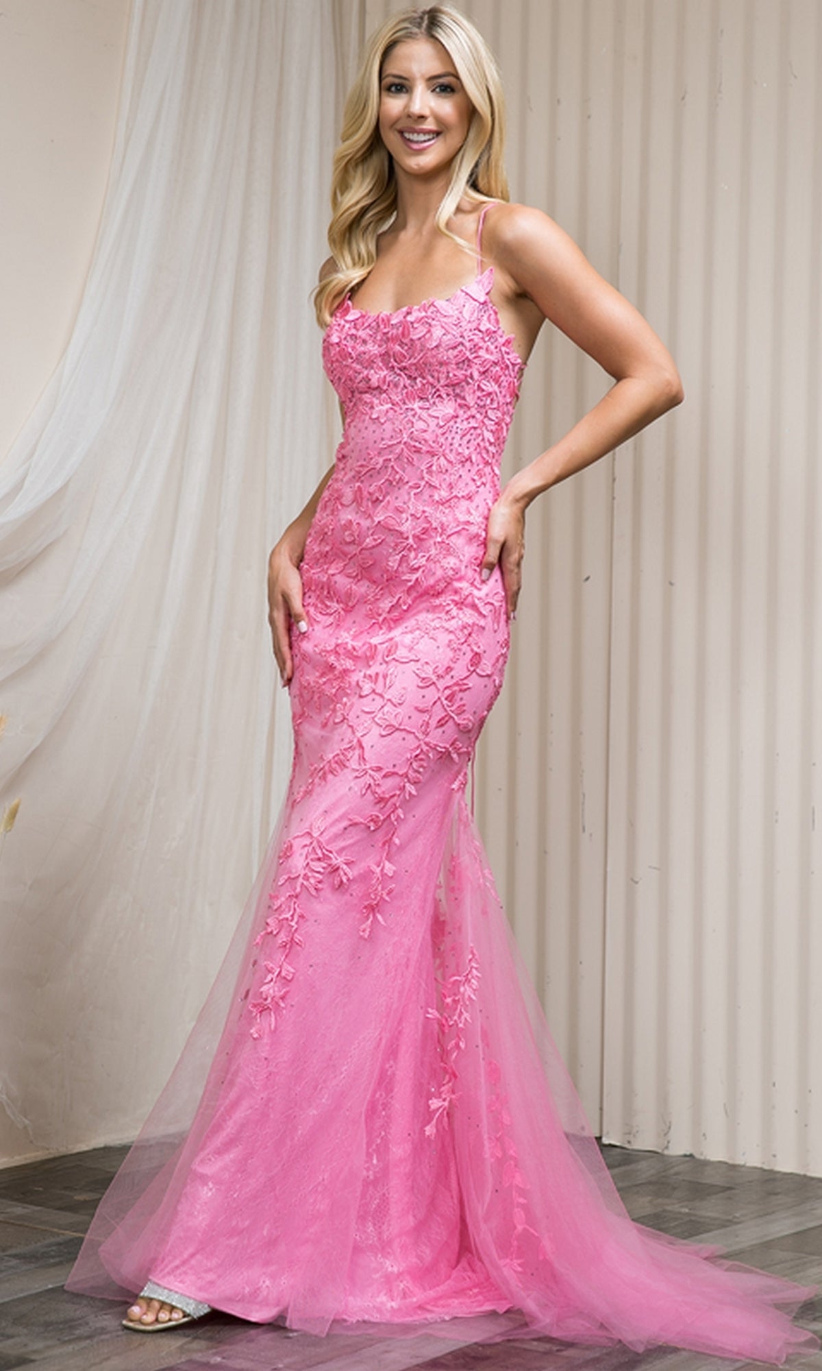 A woman poses indoors against a light draped backdrop, smiling in the Embroidered-Lace Tight Long Prom Gown 799—pink, form-fitting, with floral lace and sheer tulle accents.
