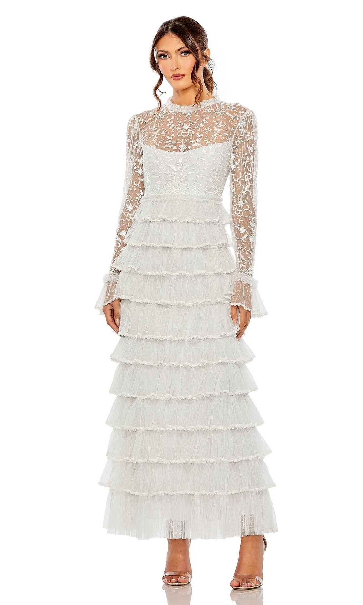 A woman wears the Long Formal Dress 8003 by Mac Duggal, featuring a sheer lace bodice, long sleeves, and a tiered ruffle skirt, standing against a plain background.