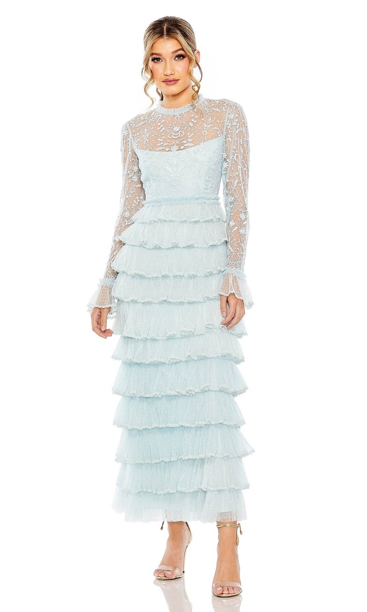 A woman wears the Long Formal Dress 8003 by Mac Duggal, featuring light blue lace, a sheer high neck, and multiple ruffled layers, paired with open-toe heels against a white background.