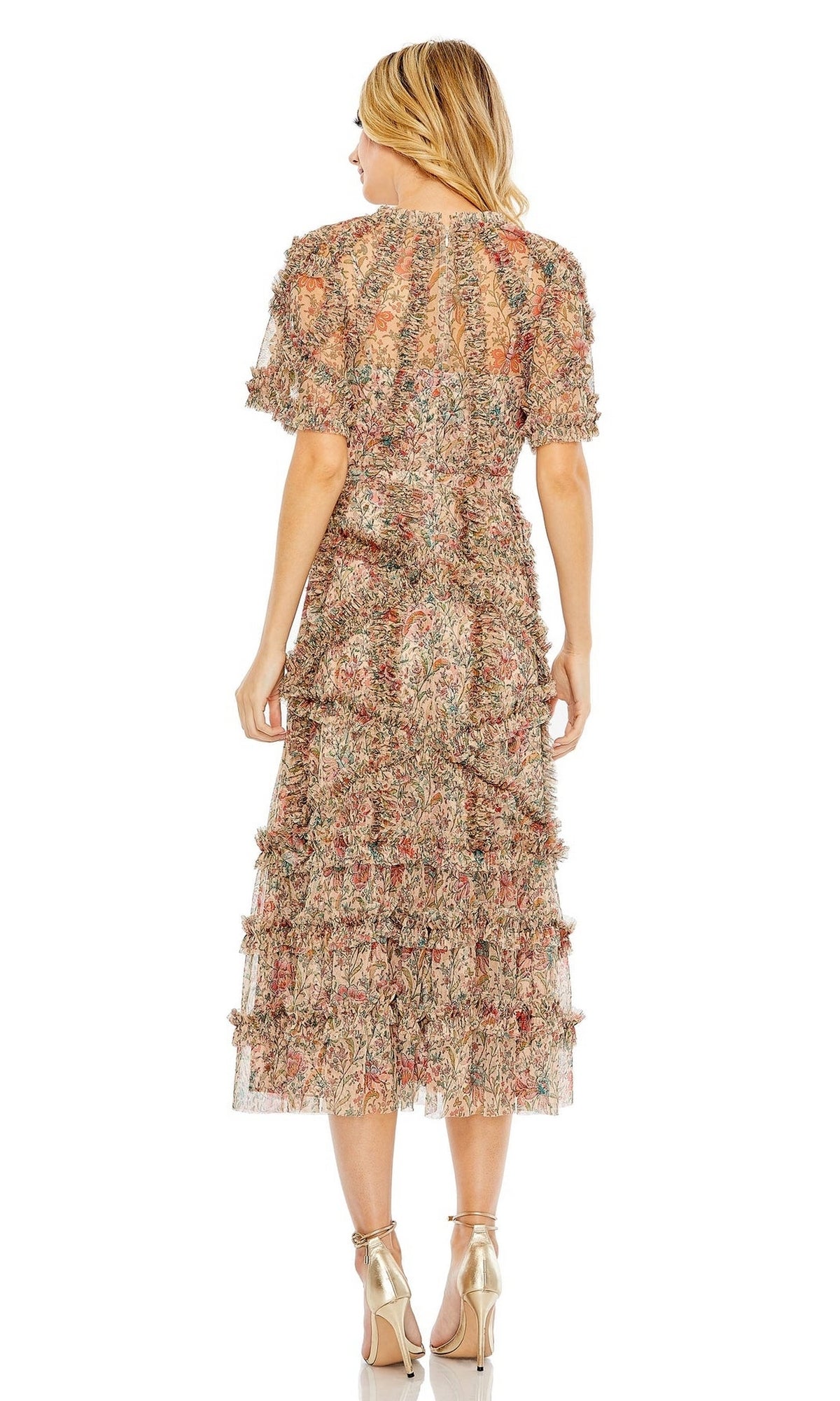 A woman faces away, wearing the Mac Duggal 8010 short-sleeve wedding-guest dress with floral print and metallic high-heeled sandals against a white background.