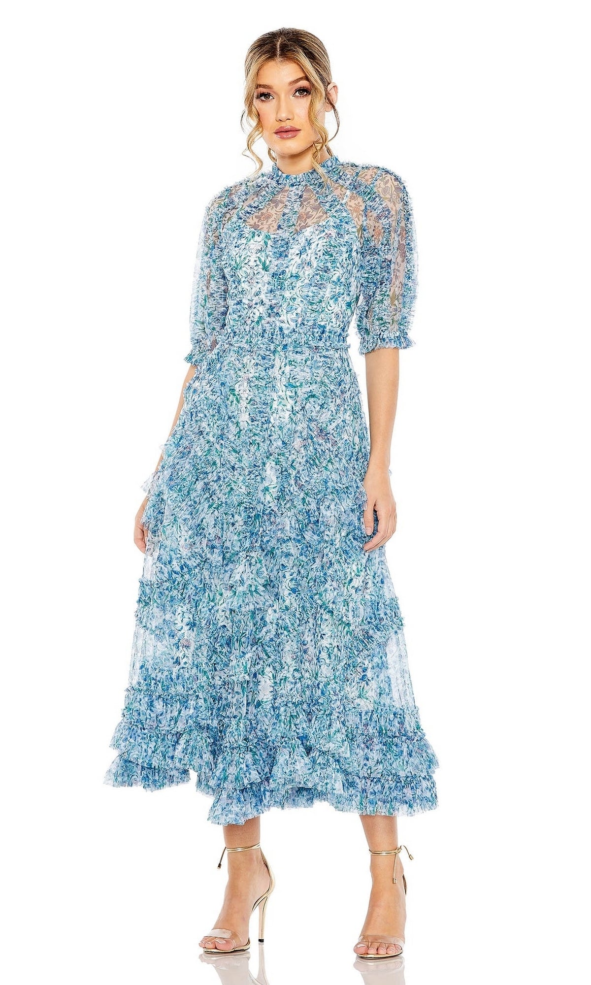 A woman stands against a white background wearing the Midi Wedding Guest Dress 8011 by Mac Duggal—a blue floral midi dress with puffed sleeves and ruffled hem—paired with strappy nude heels, perfect for any wedding guest.
