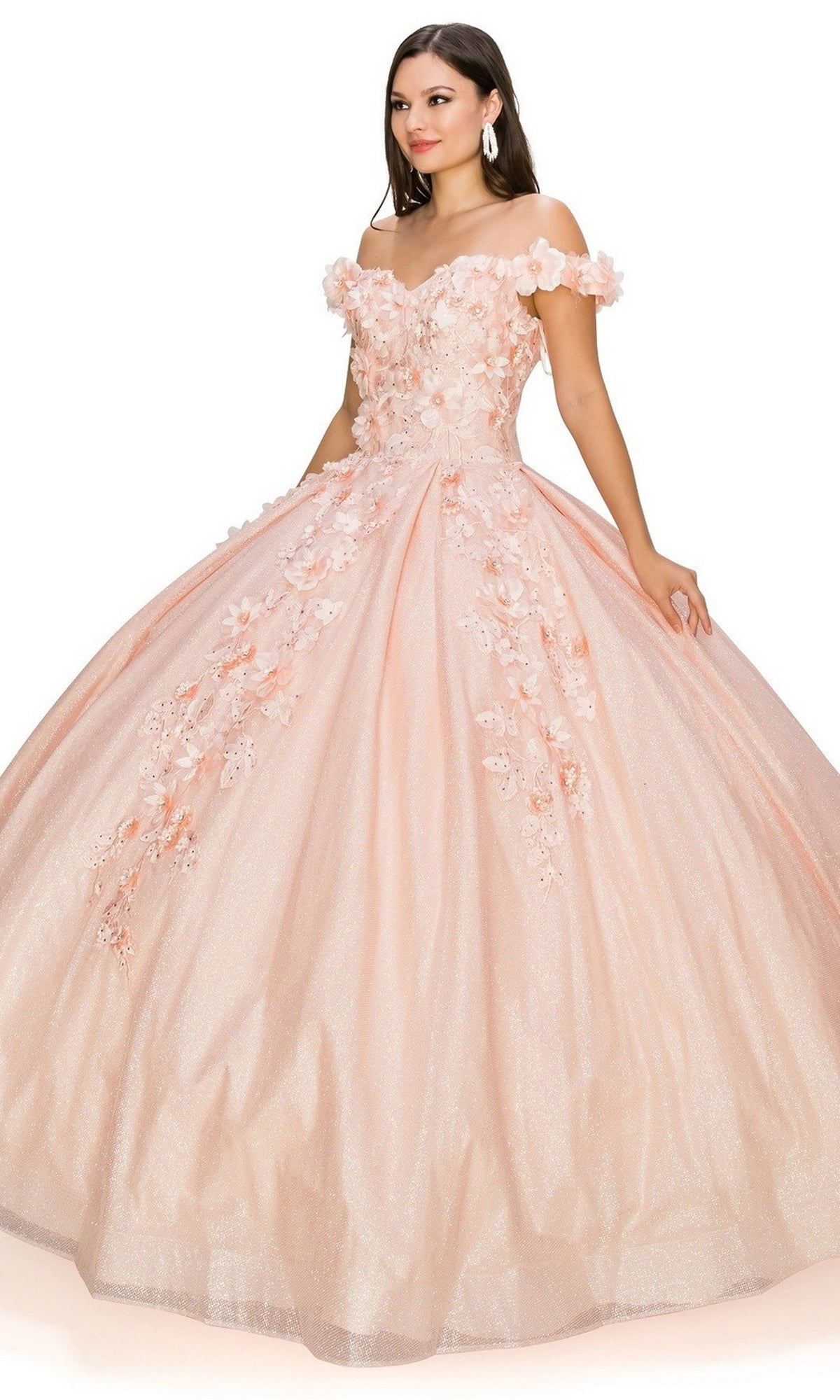 A woman wearing the Quinceanera Ball Gown 8020J, featuring an off-the-shoulder design, glitter skirt, and 3D floral details, stands against a white background.