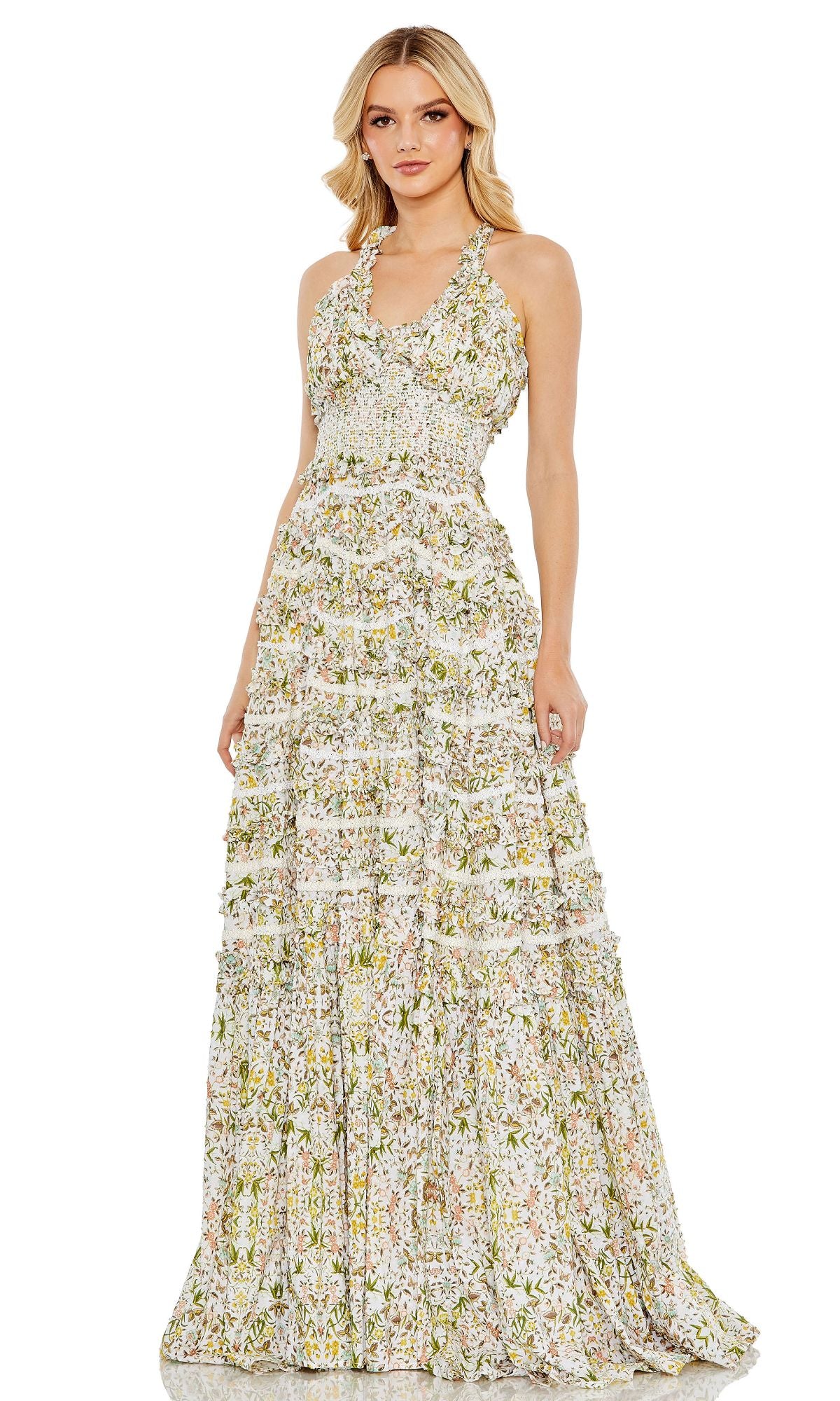 A woman wears the Mac Duggal 8023 Long Floral-Print Formal Dress, featuring a sleeveless fitted bodice and tiered floor-length skirt, posing against a plain white background.
