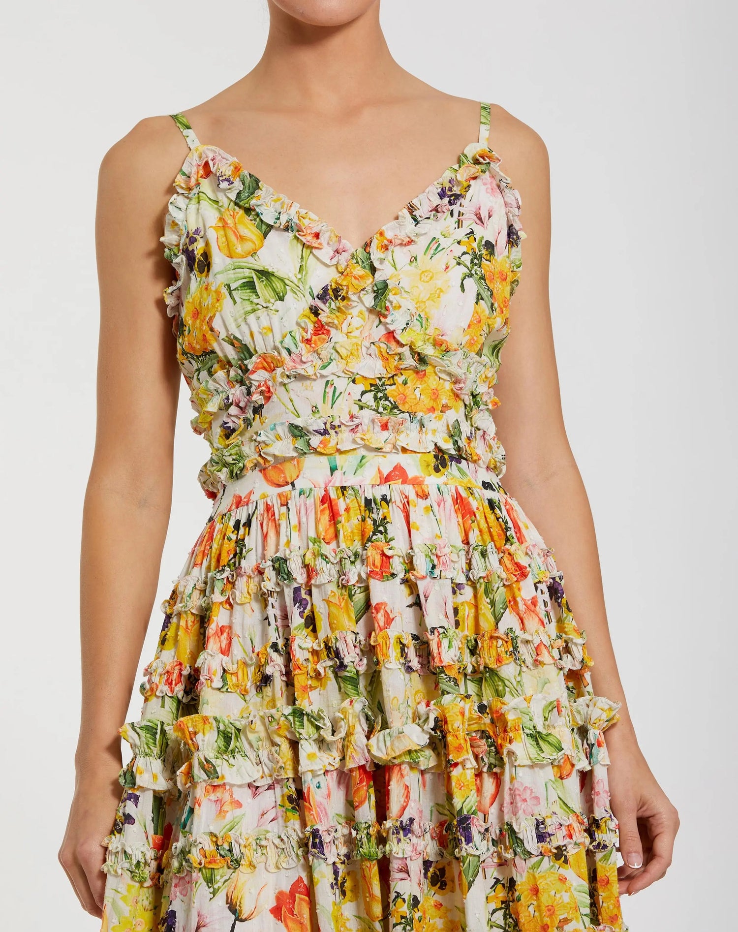 A person wearing the Mac Duggal 8026 Midi Print Wedding Guest Dress, featuring a sleeveless V-neck, ruffled trim, and fitted bodice—perfect for attending weddings.