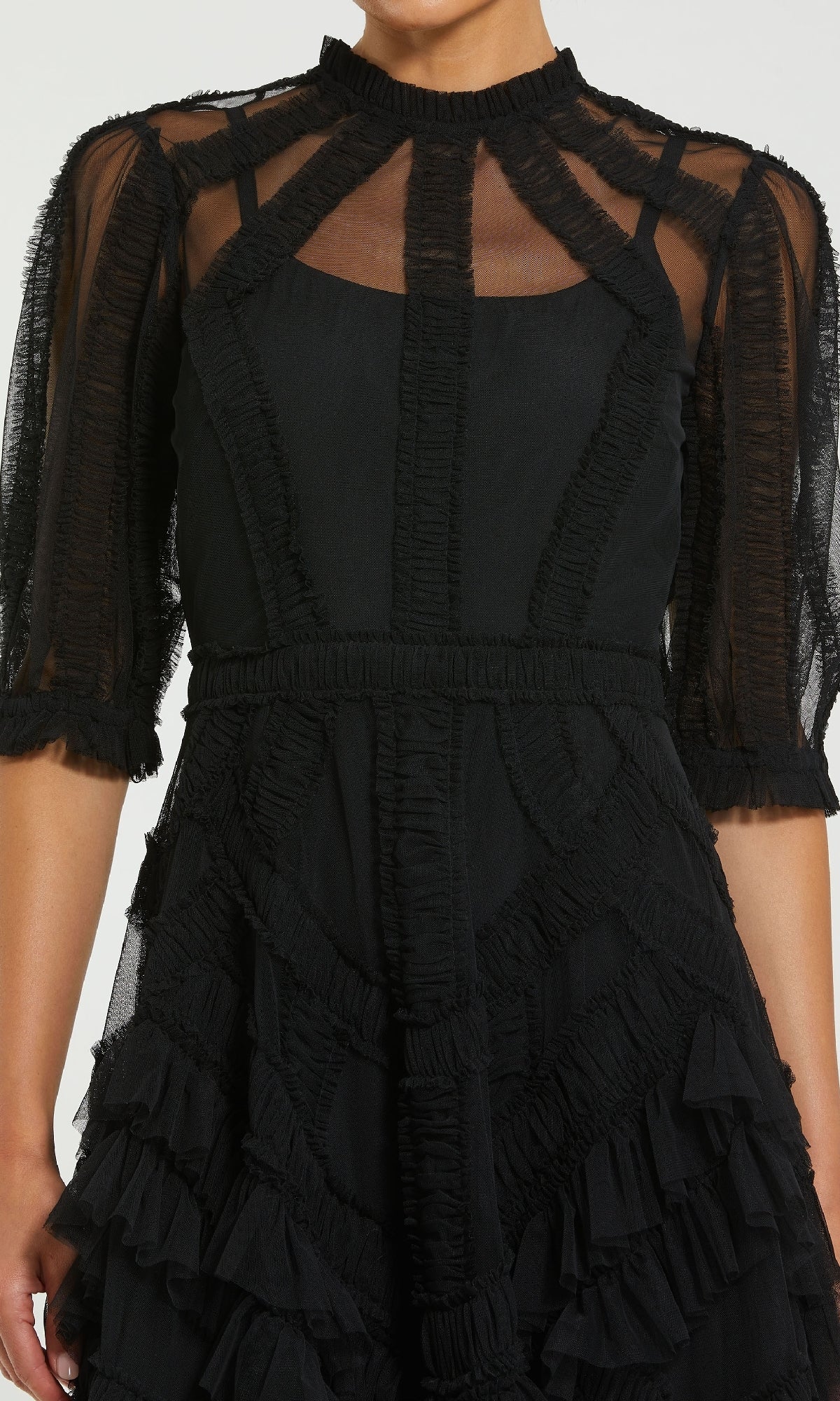 A person wearing the Mac Duggal 8058 Ruffled Midi Wedding-Guest Dress, featuring black sheer mesh panels, textured ruffle details, and elbow-length sleeves.