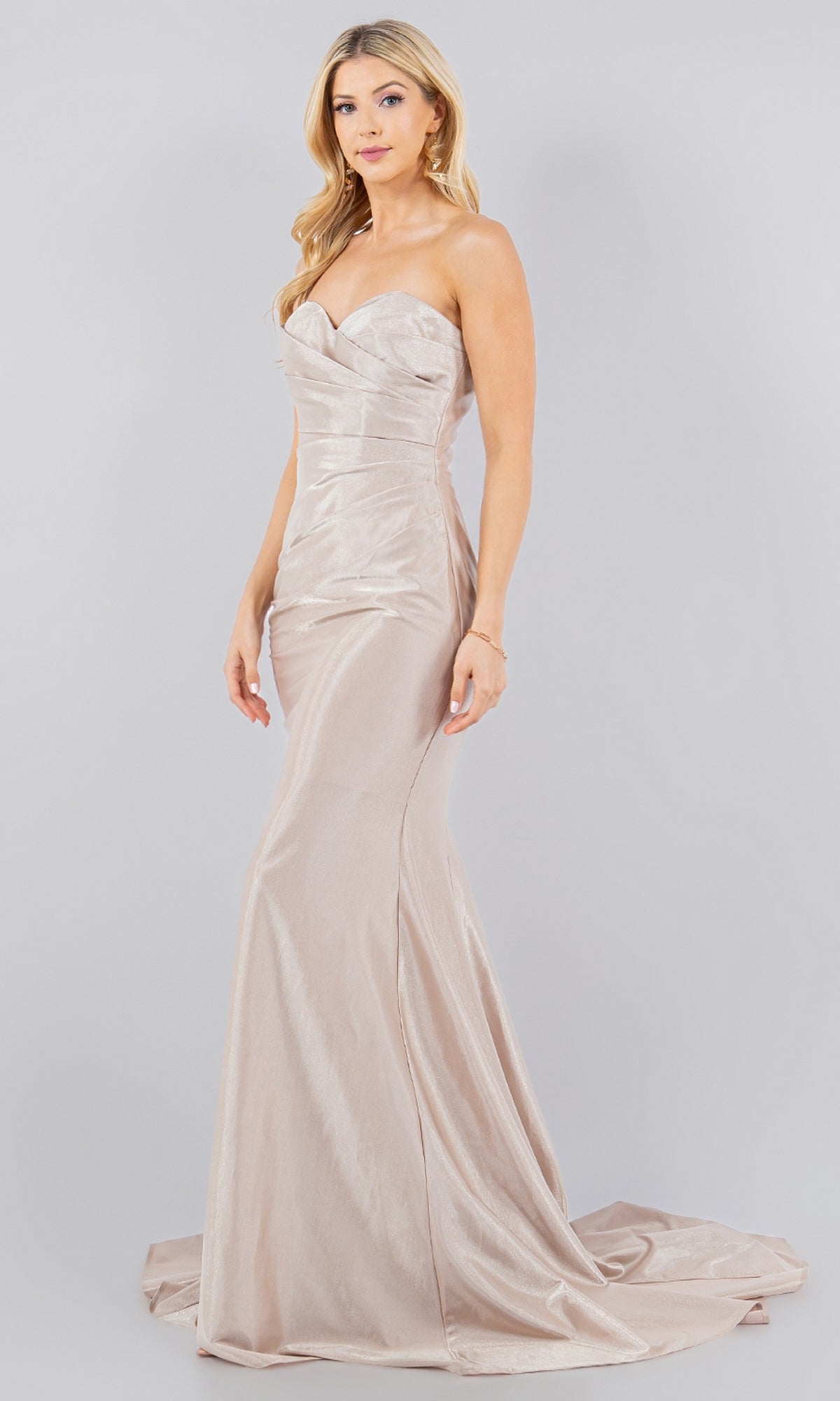 A woman models the Cinderella Couture 8083J, a strapless satin mermaid prom dress in floor-length champagne, against a plain light gray background.