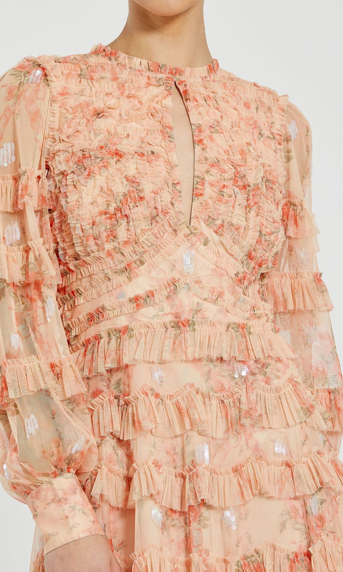 Close-up of a person wearing the Mac Duggal 8094 Peach Floral Wedding Guest Dress, featuring long sleeves, ruffles, sheer fabric, and a small keyhole neckline—perfect for romantic occasions.
