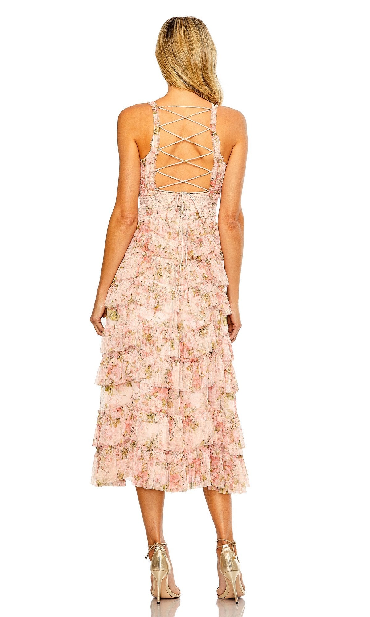 A woman stands facing away, wearing the Midi Wedding Guest Dress: Mac Duggal 8100—a sleeveless floral midi dress with a lace-up back, tiered skirt, and metallic heels.